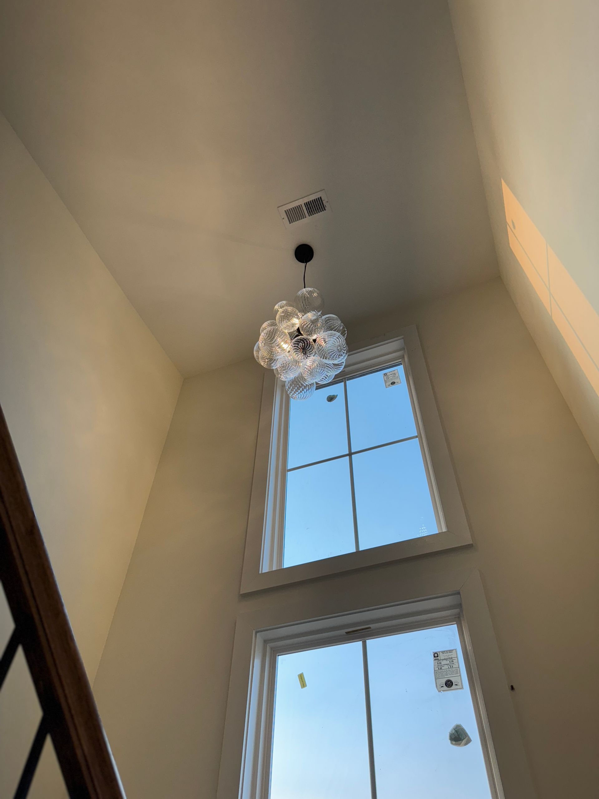 High angle view of a tall room with two large windows and a chandelier.