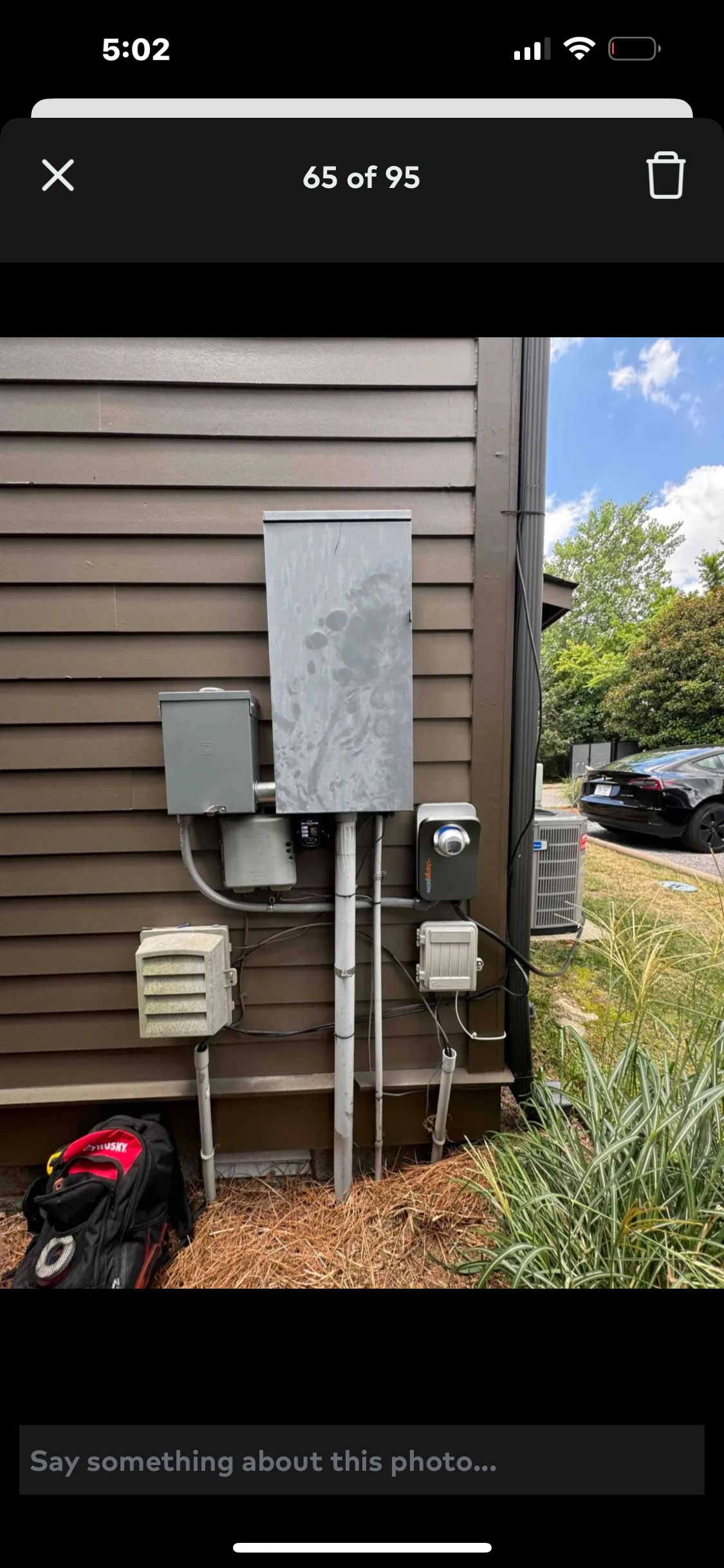 Electrical equipment mounted on a brown building exterior with green grass and mulch.