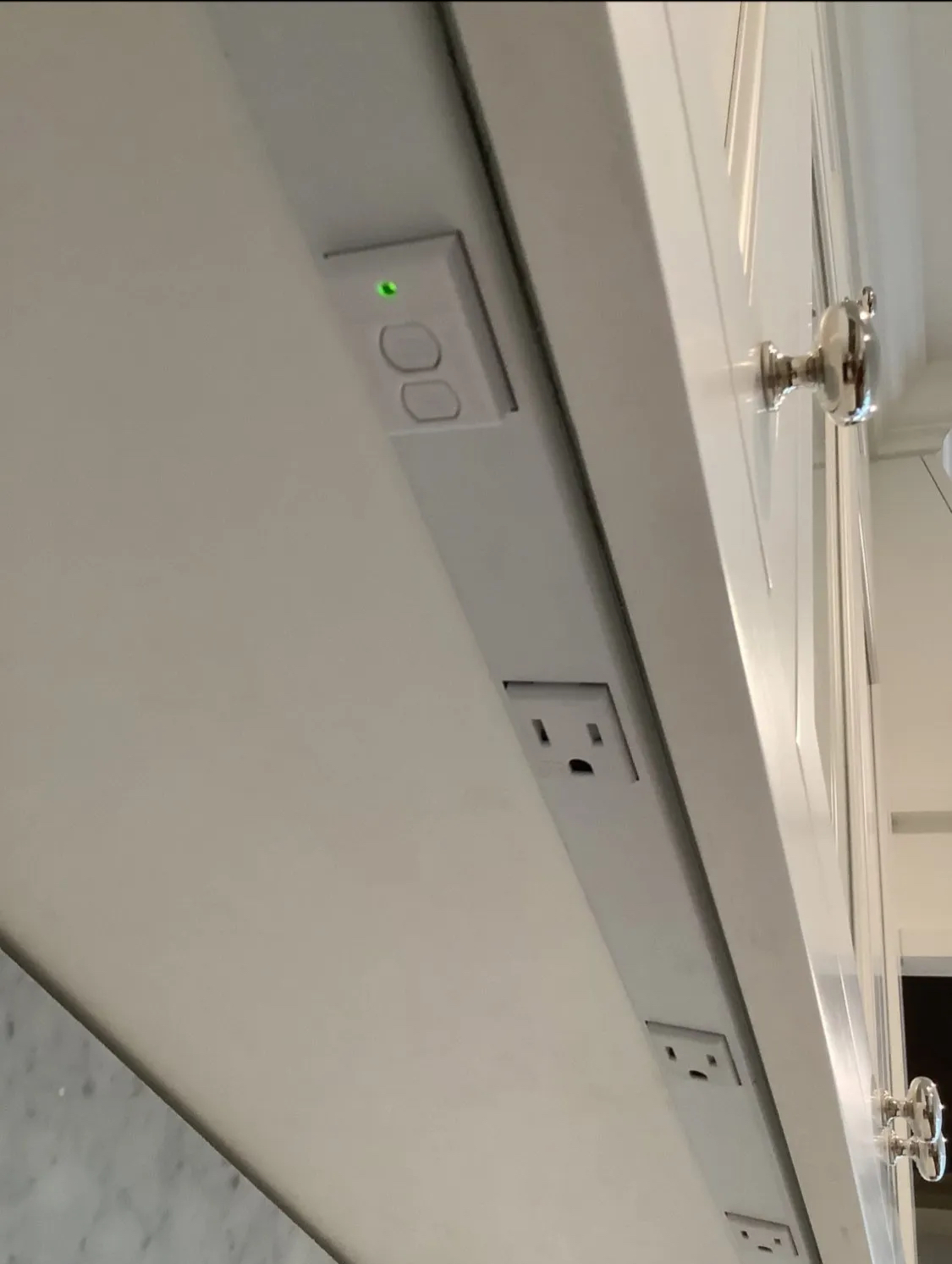 White kitchen cabinets with light switches and outlets on the underside.