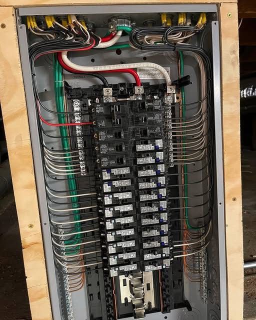 Electrical panel with numerous wires, breakers, and grounding. Wires are various colors.