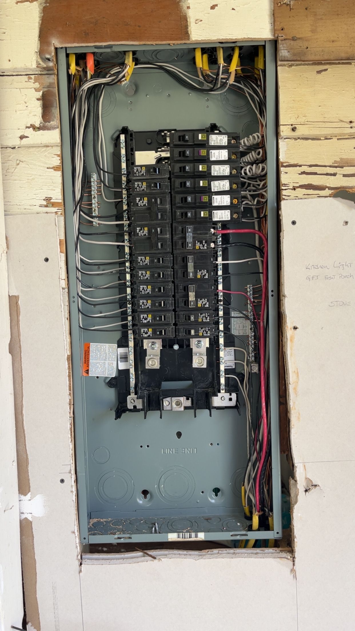 Electrical panel in a wall, showing burnt areas and wiring, potentially a fire hazard.
