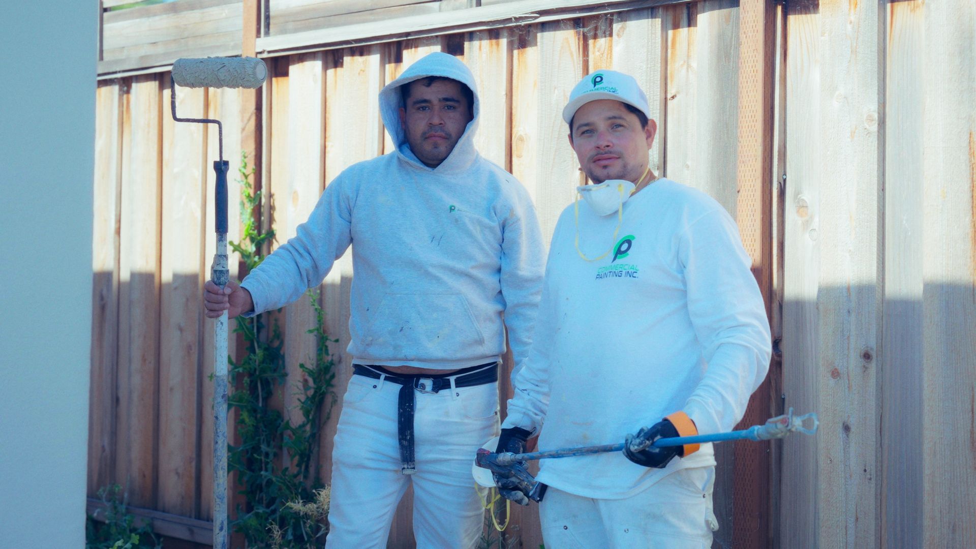 Two men are painting a building with a scissor lift.