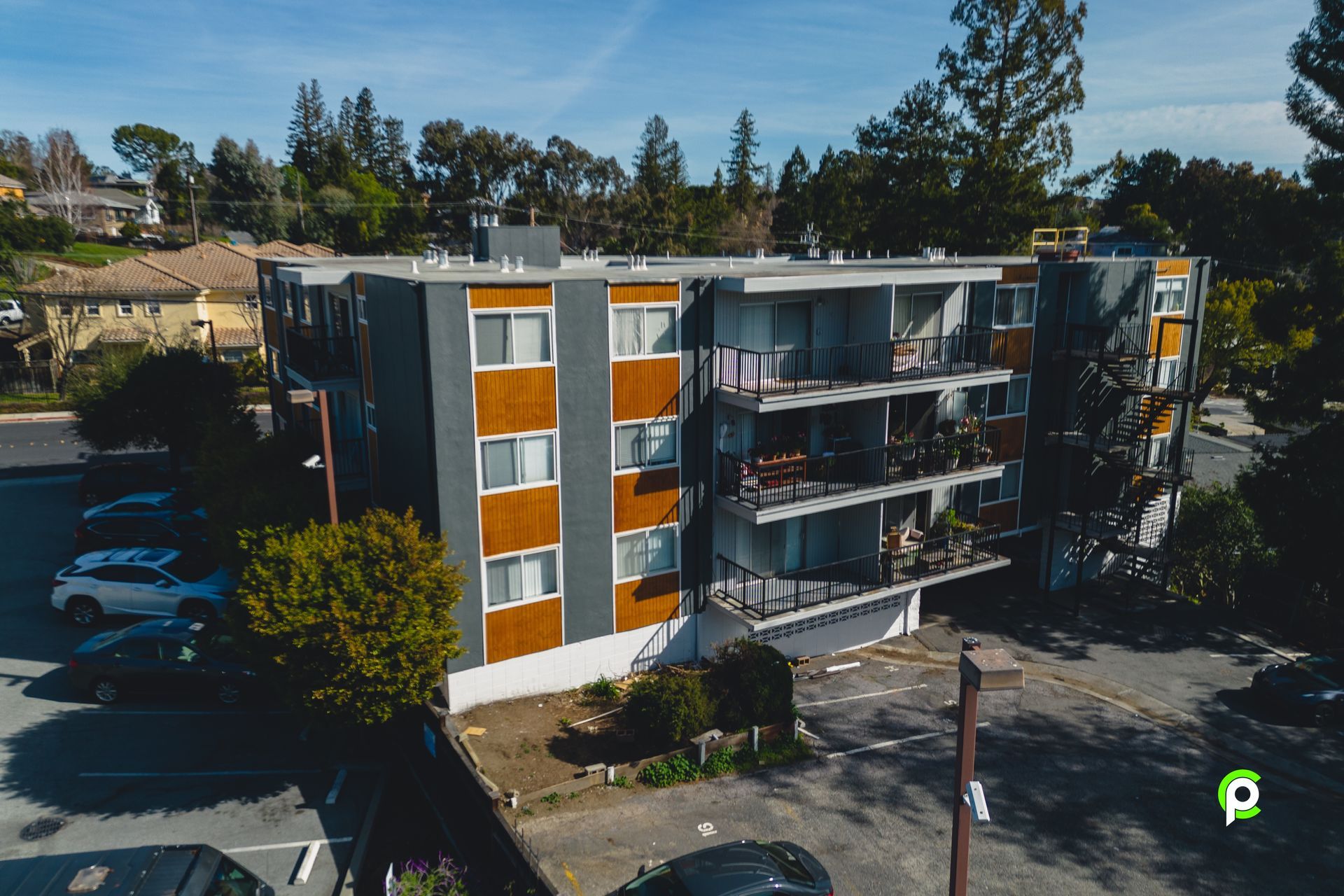 An aerial view of a apartment building with cars parked in front of it