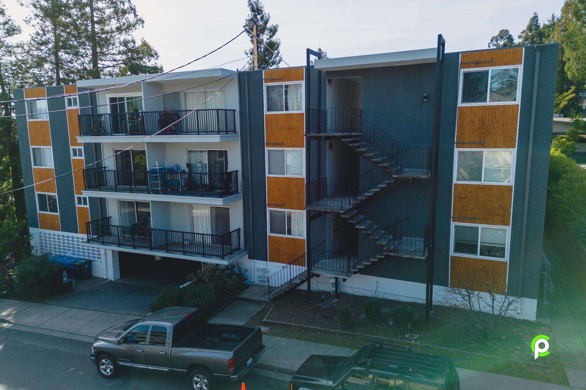 An aerial view of a large apartment building with a truck parked in front of it.