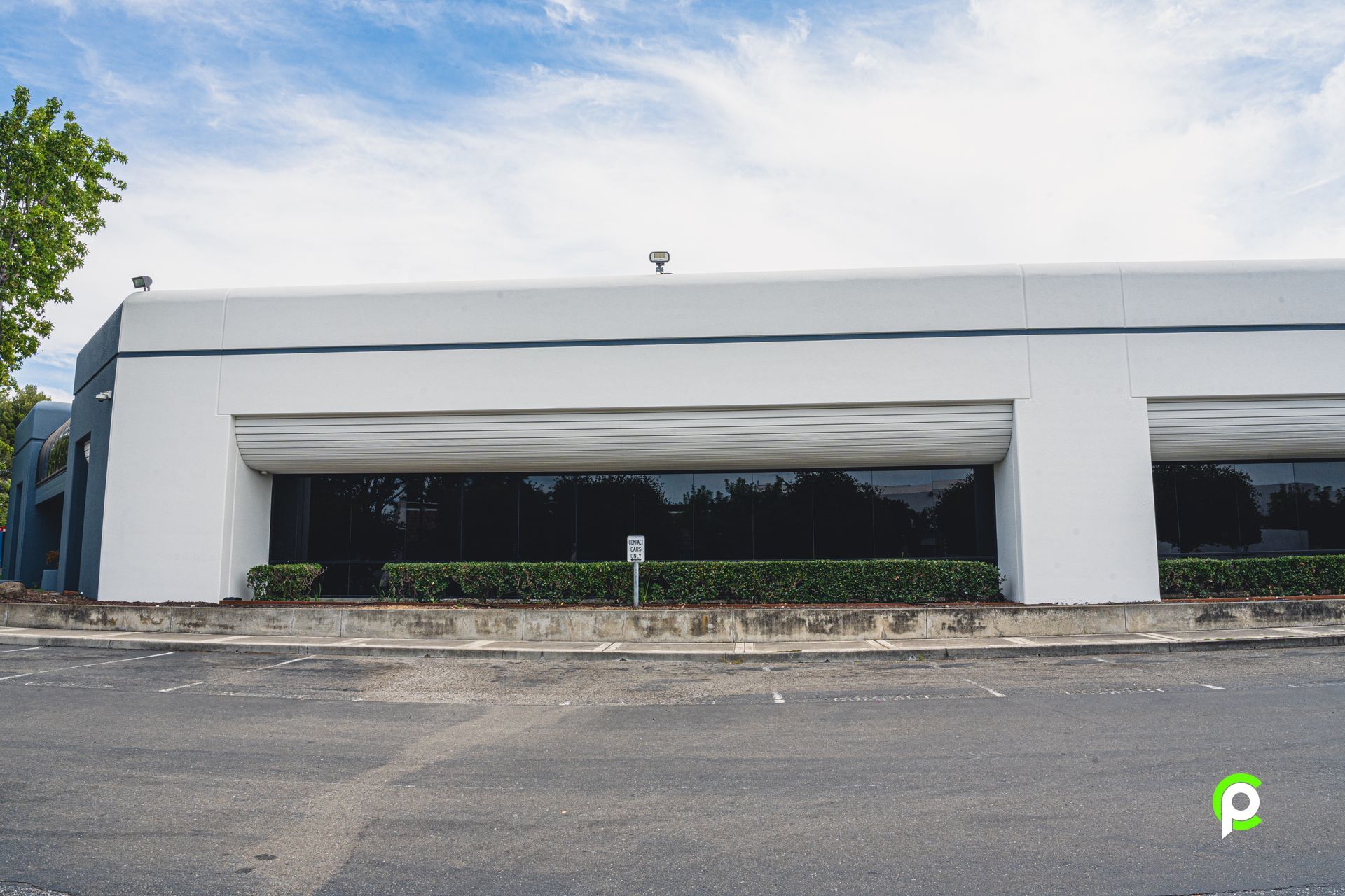 A large white building with a lot of windows is sitting on the side of the road.