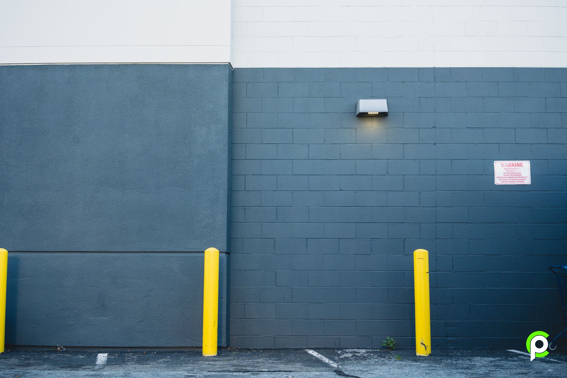 A parking lot with a brick wall and yellow poles.