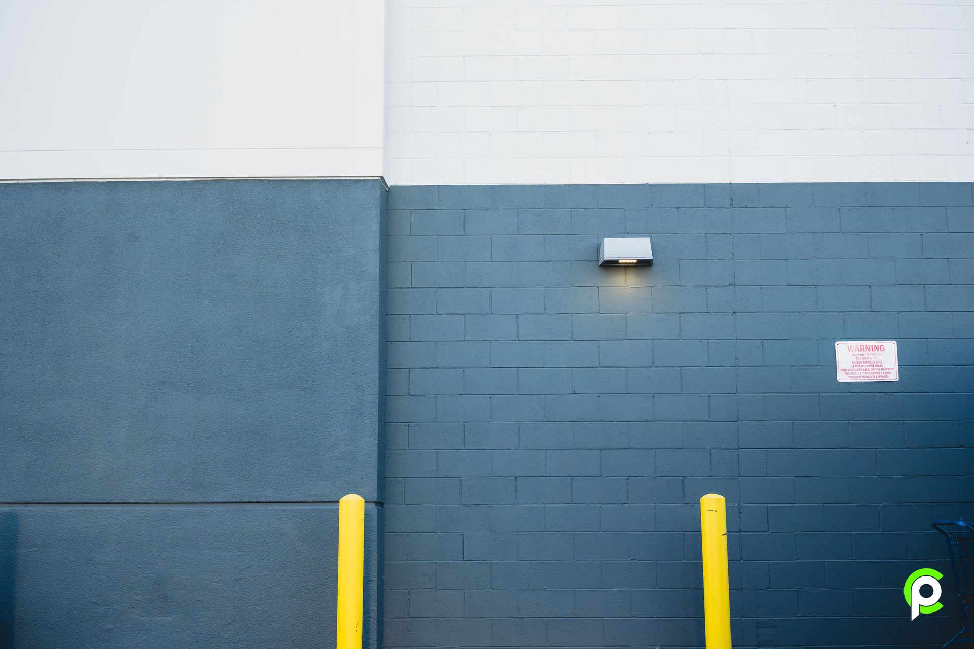 A blue brick wall with yellow poles in front of it