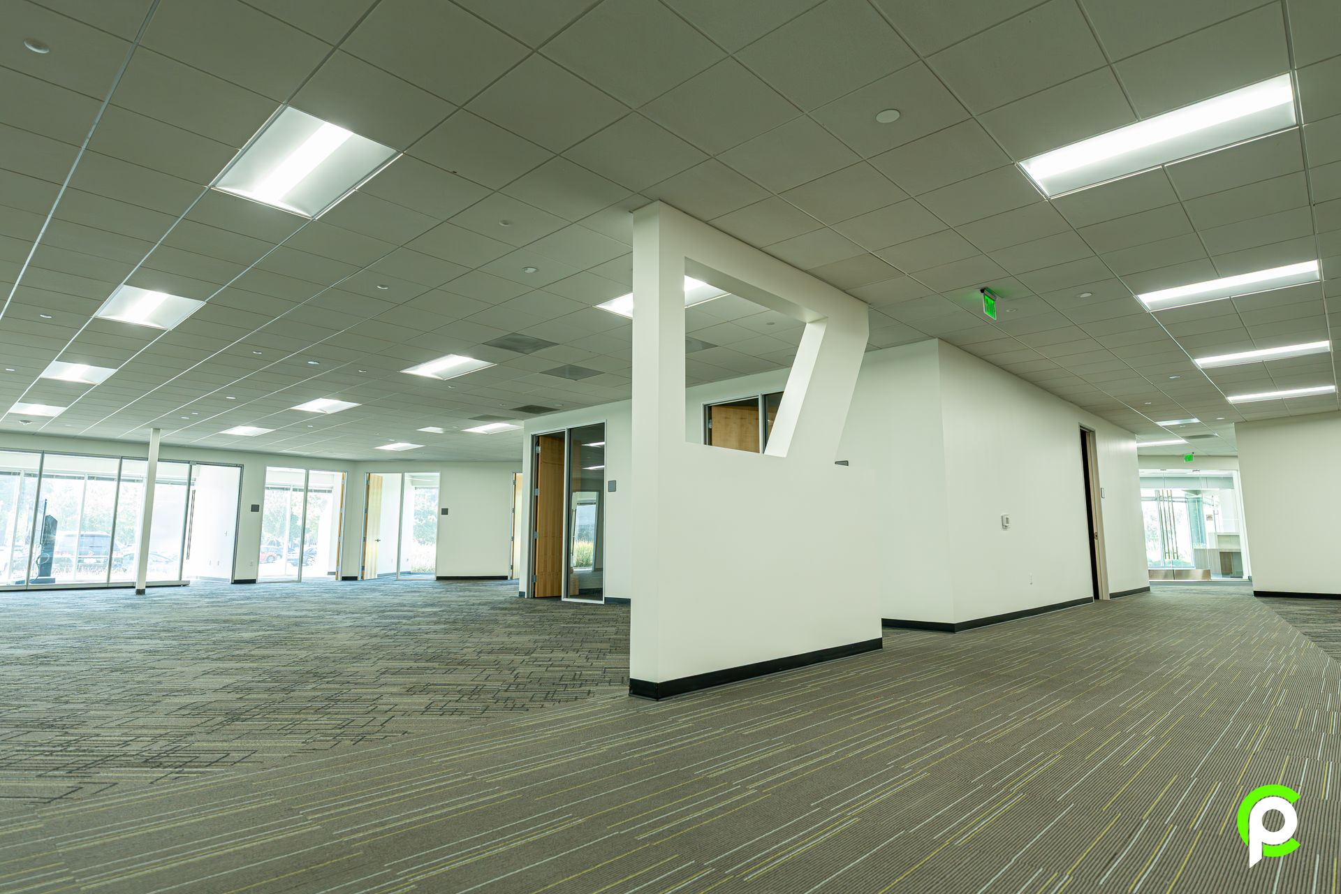 A large empty office building with a lot of windows and a carpeted floor.