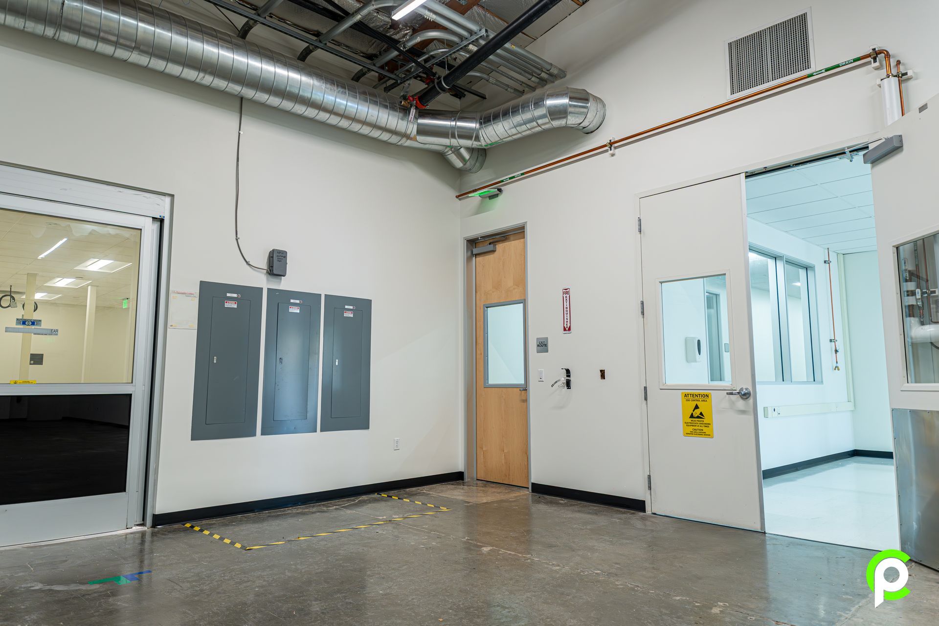 An empty room with a lot of doors and electrical panels on the wall.