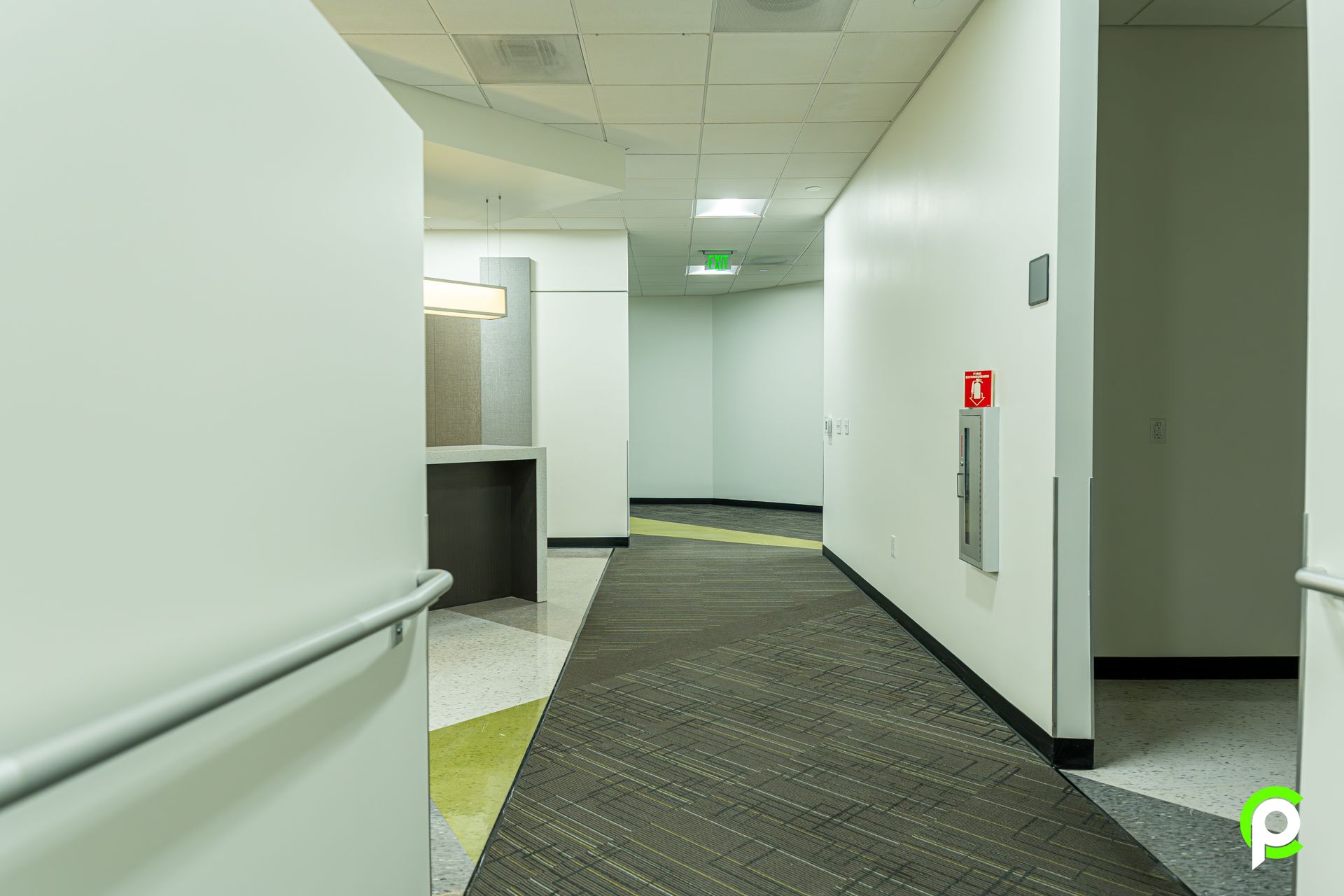 A long hallway in a building with a fire extinguisher on the wall.