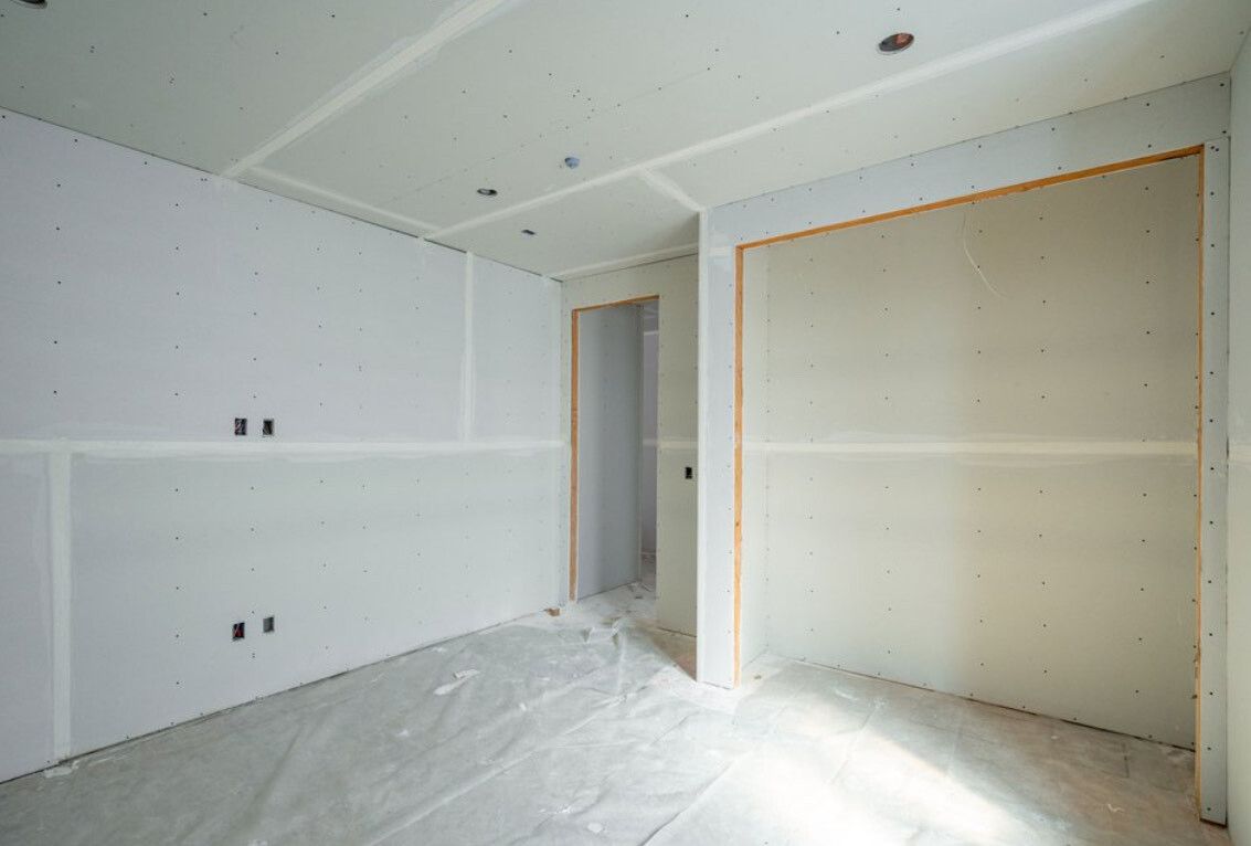 Interior room under construction with drywall on walls and ceiling.
