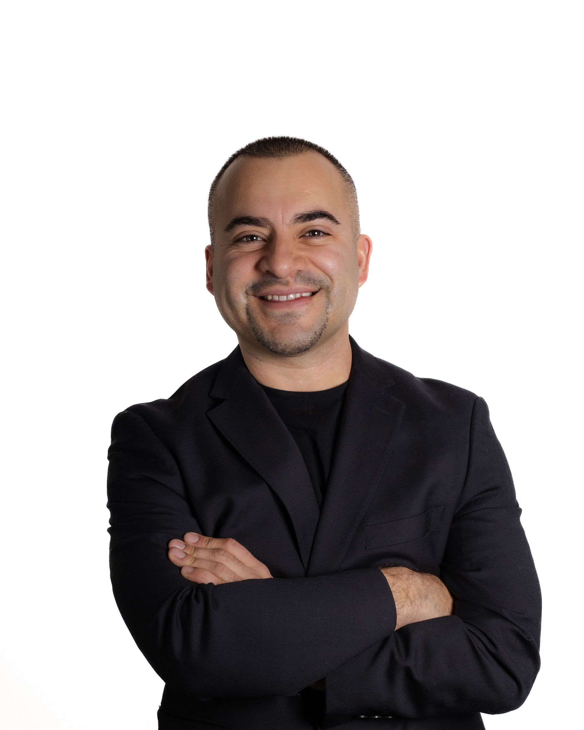 A man in a suit is smiling with his arms crossed