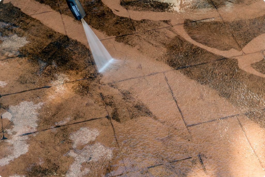 A person is cleaning a tiled floor with a high pressure washer.