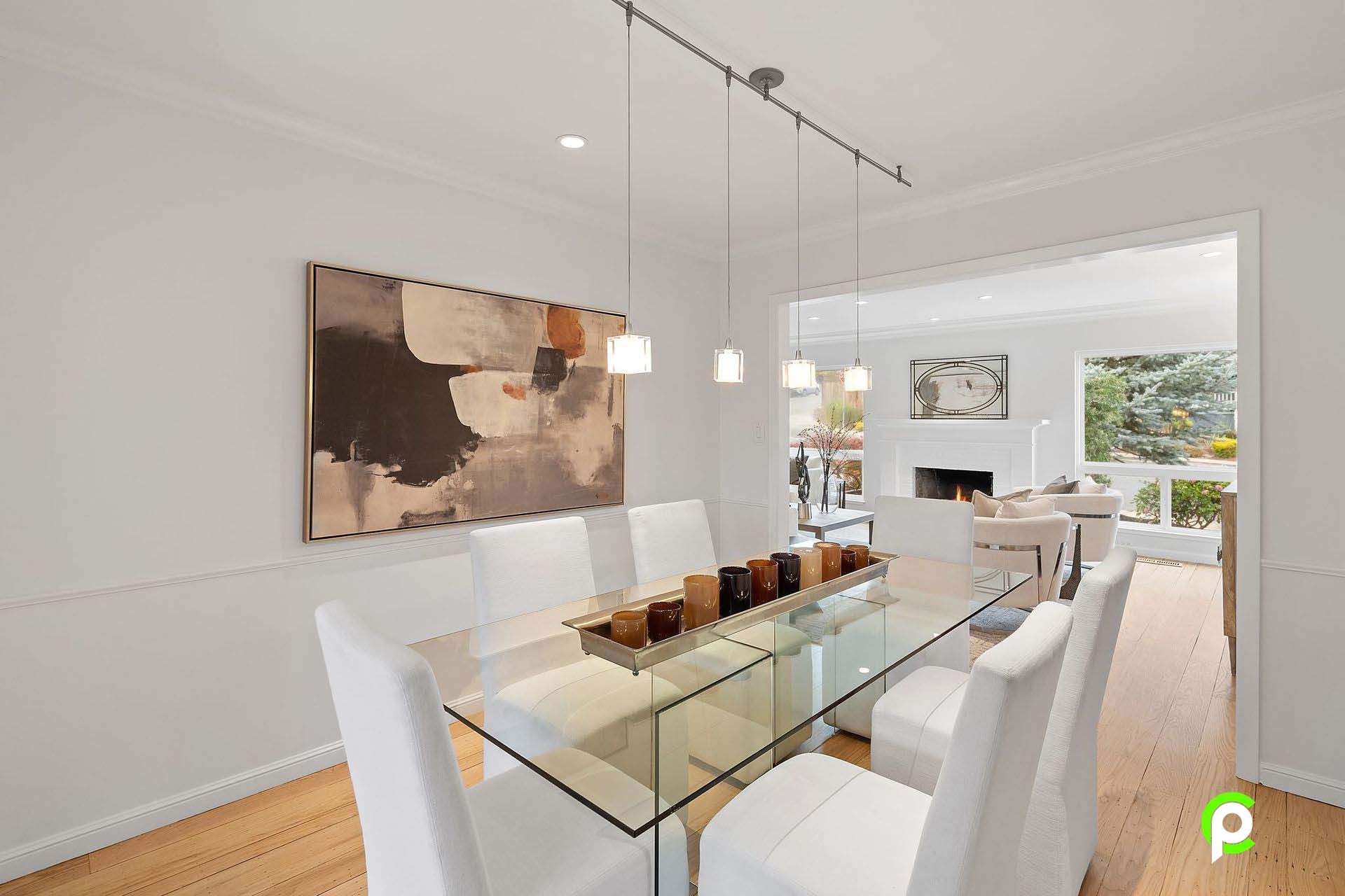 A dining room with a glass table and white chairs