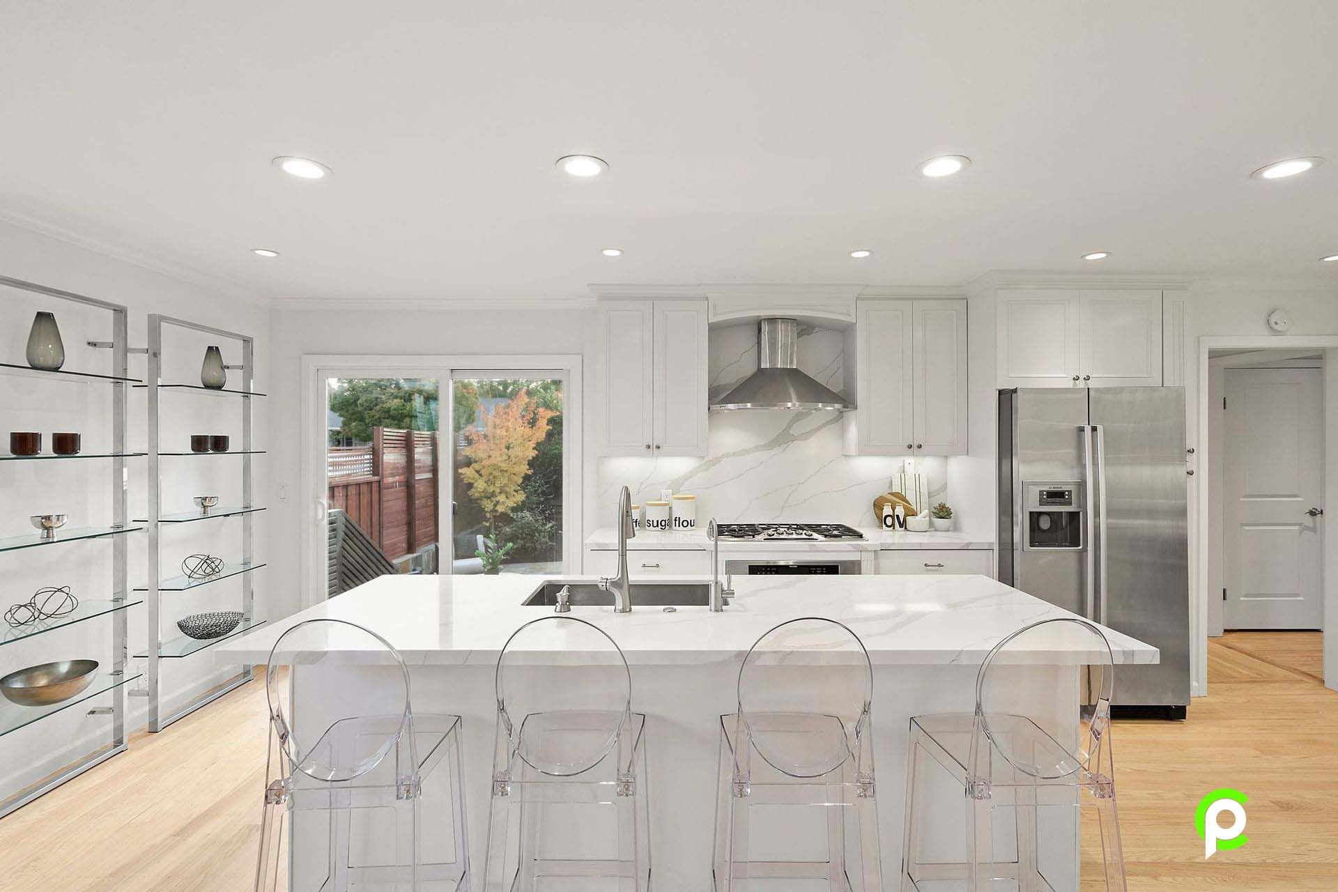 A kitchen with white cabinets , stainless steel appliances and a large island.
