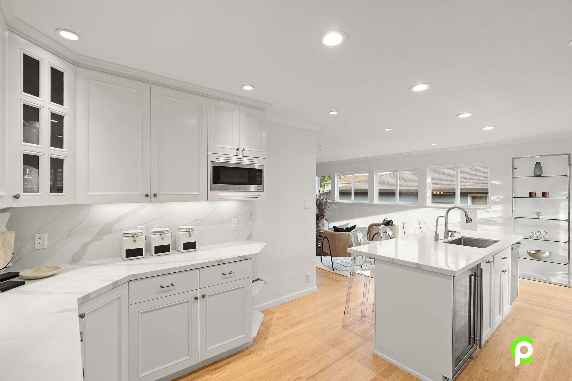 A kitchen with white cabinets , stainless steel appliances , and a large island.