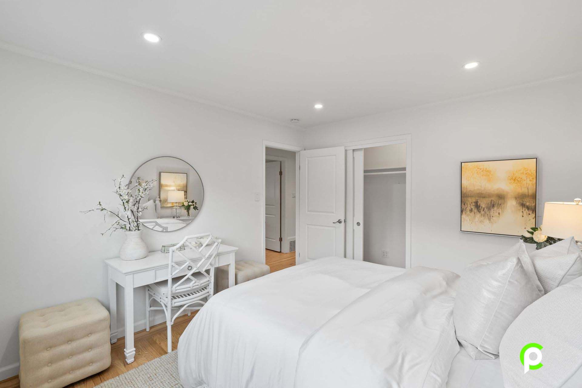 A bedroom with a bed , desk , chair and mirror.