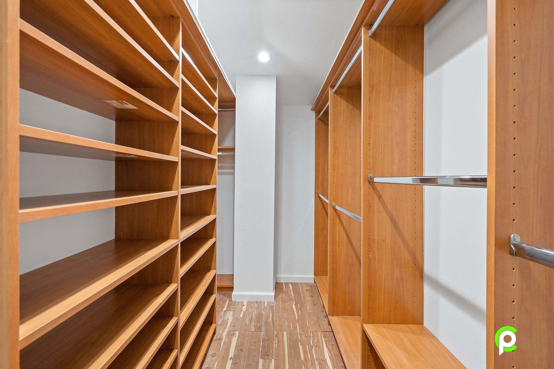 A walk in closet with wooden shelves and hanging racks