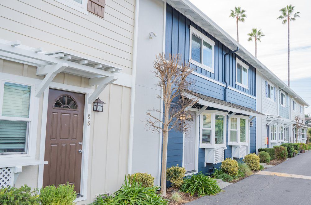 A blue and white apartment building with palm trees in the background.