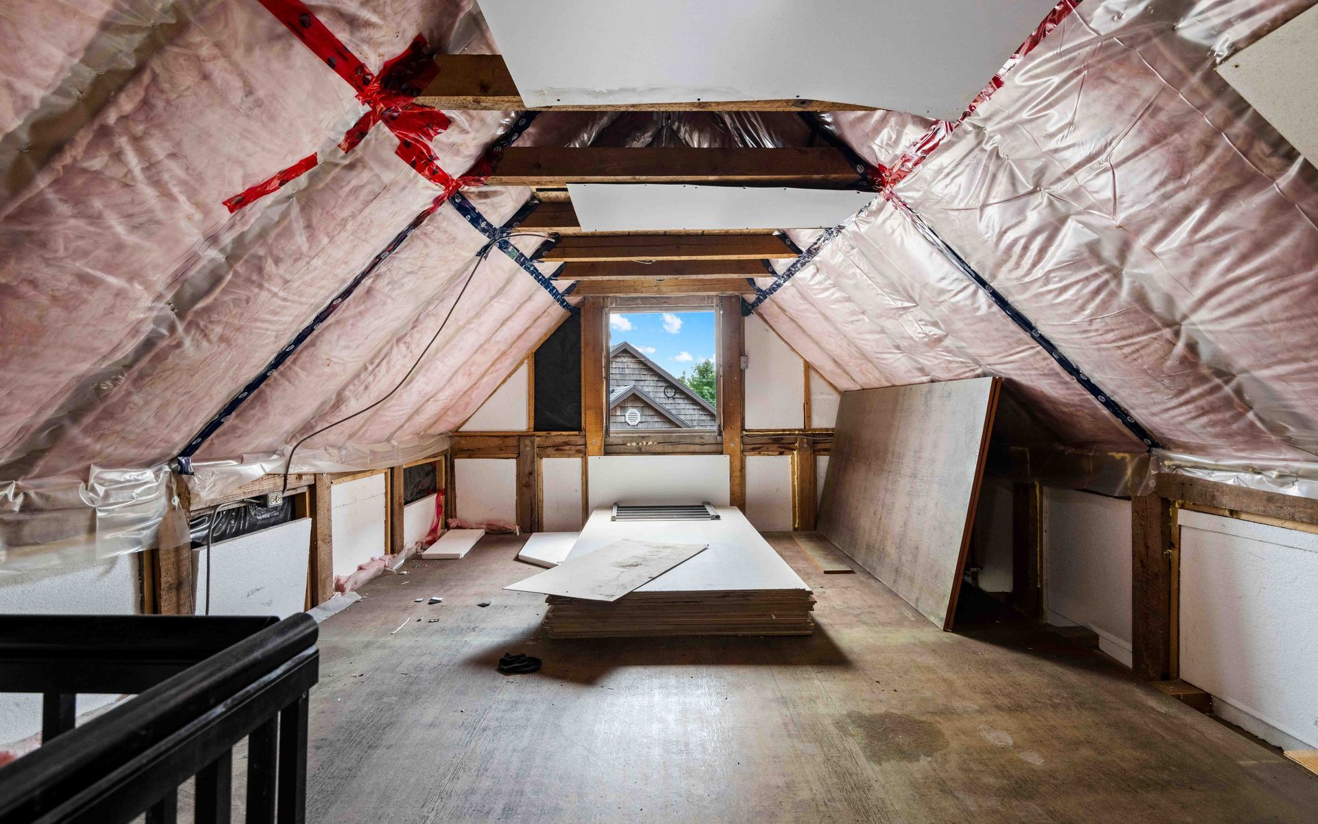 An attic with a lot of insulation and a window.