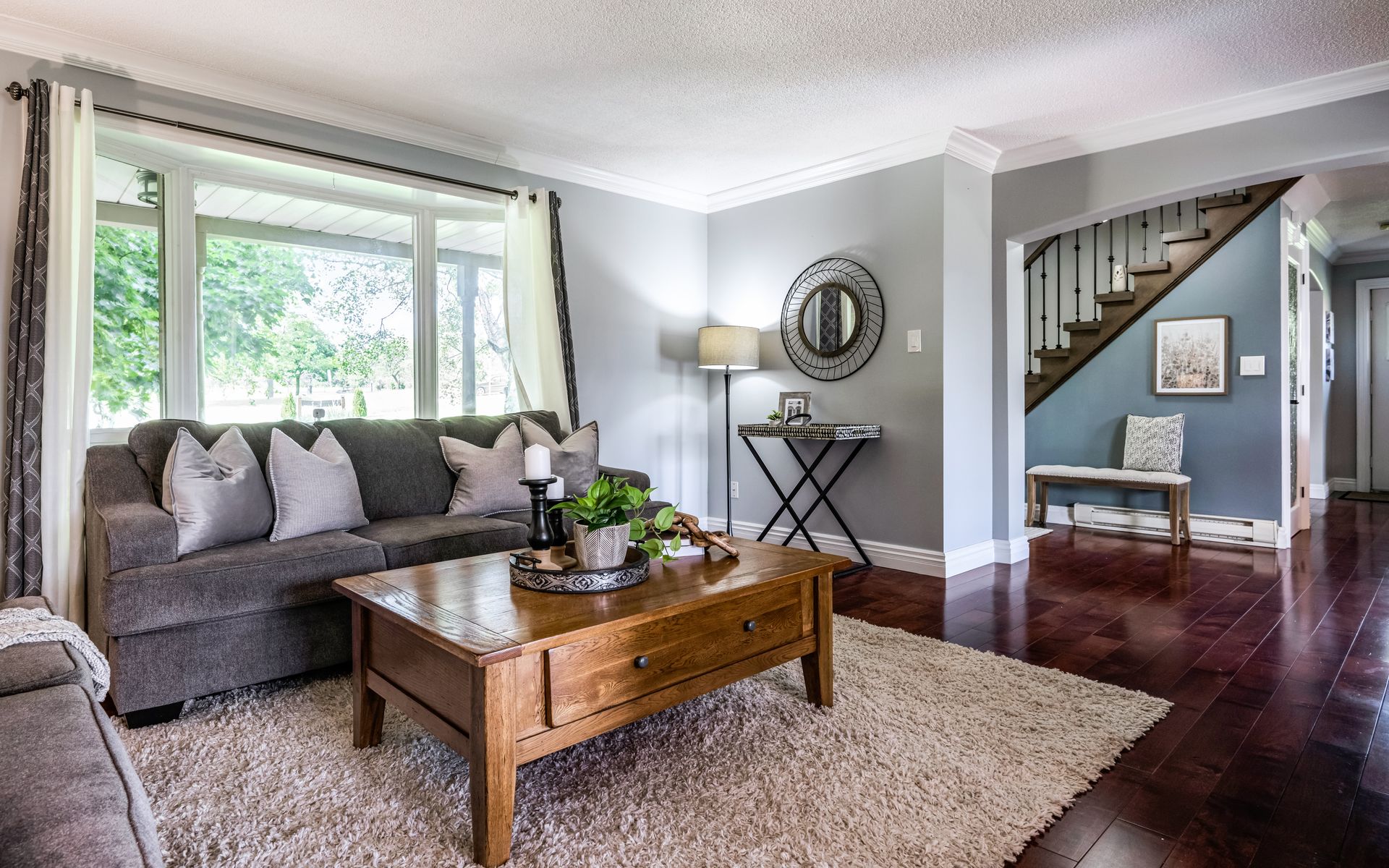 A living room with a couch , coffee table , rug and stairs.