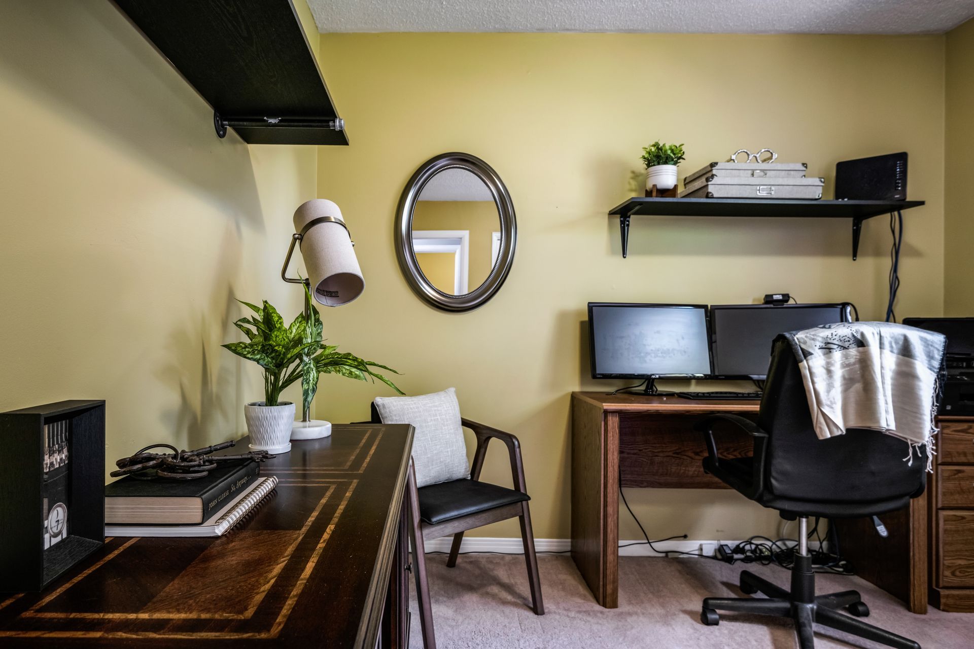 A home office with a desk , chair , computer and mirror.