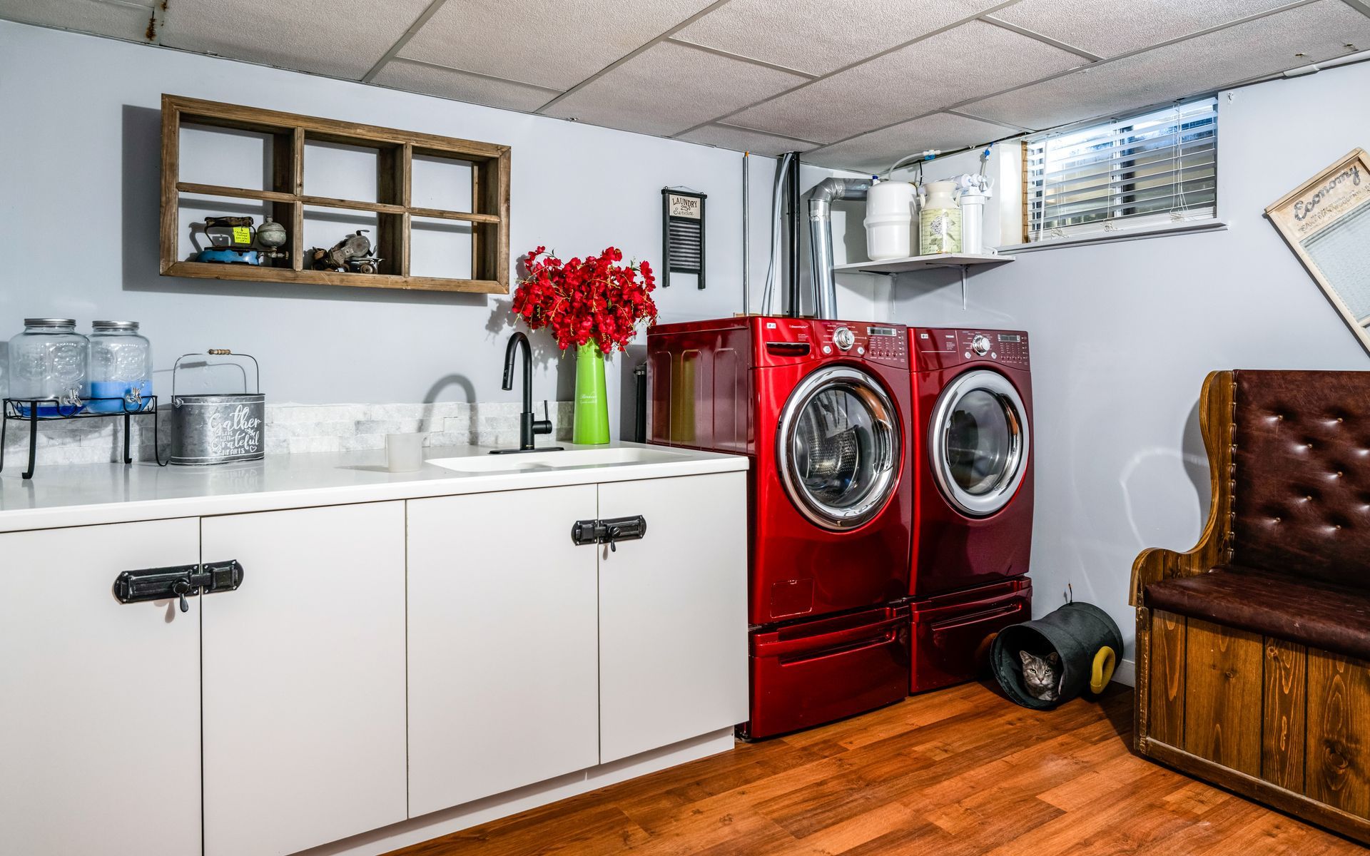 A laundry room with two red washers and two red dryers.