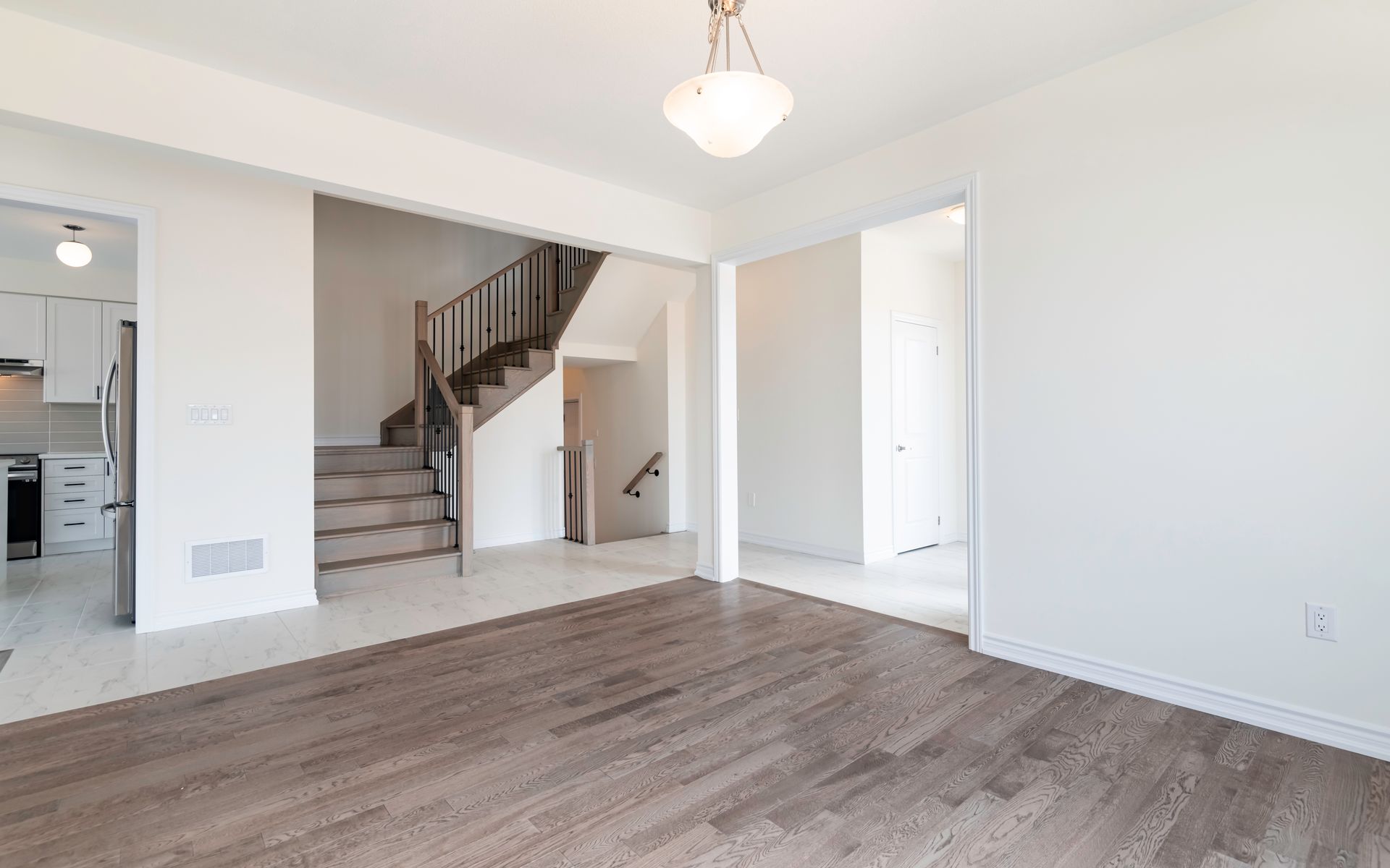 An empty living room with hardwood floors and stairs in a house.