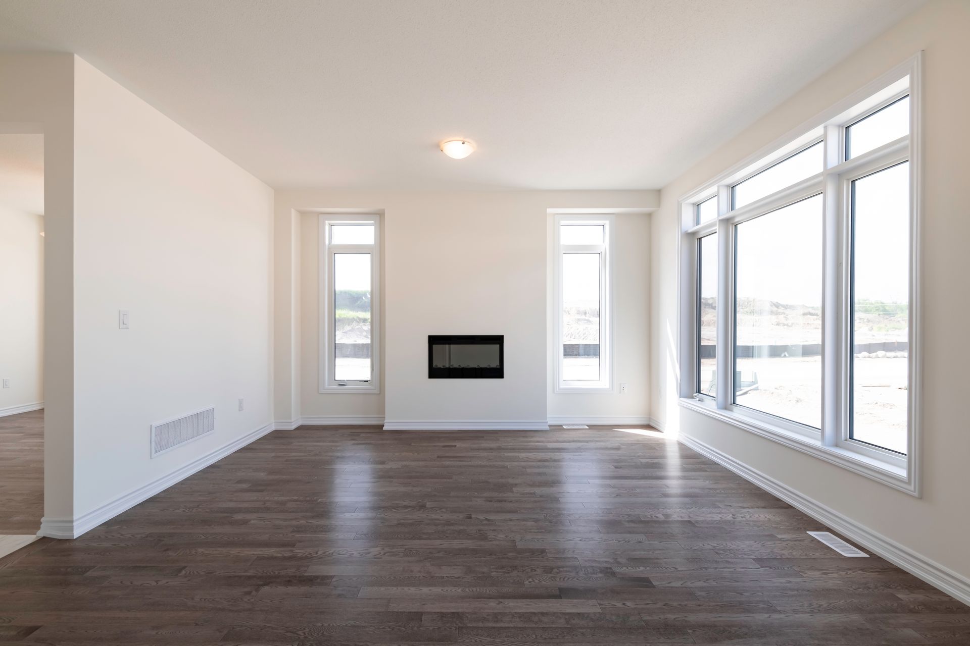An empty living room with hardwood floors and a fireplace.