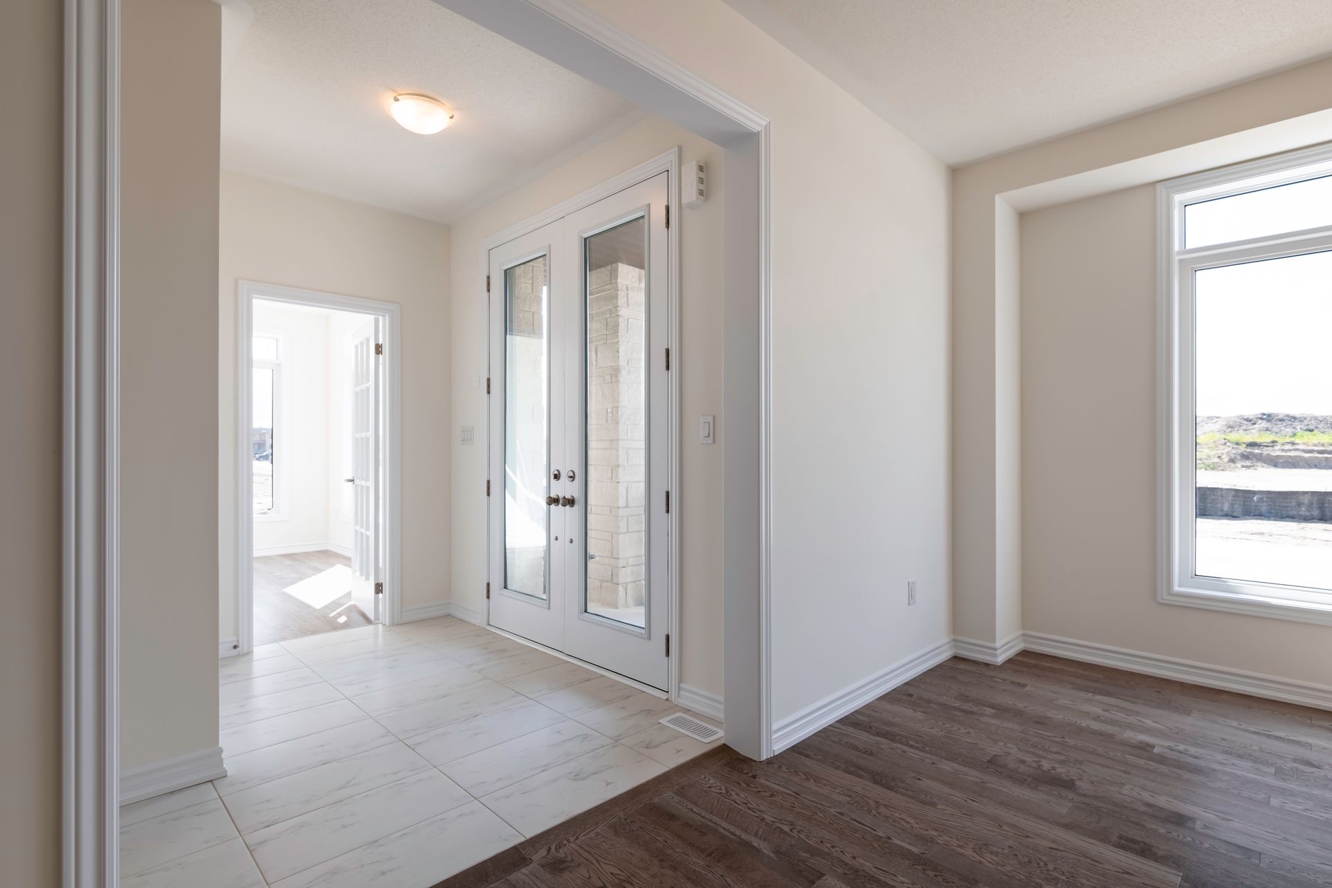 An empty hallway in a house with hardwood floors and white walls.