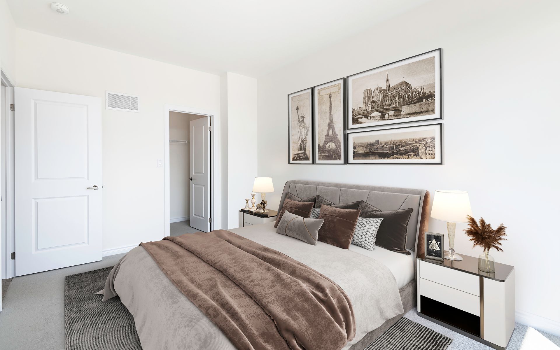 A bedroom with a bed , nightstands , lamps and pictures on the wall.