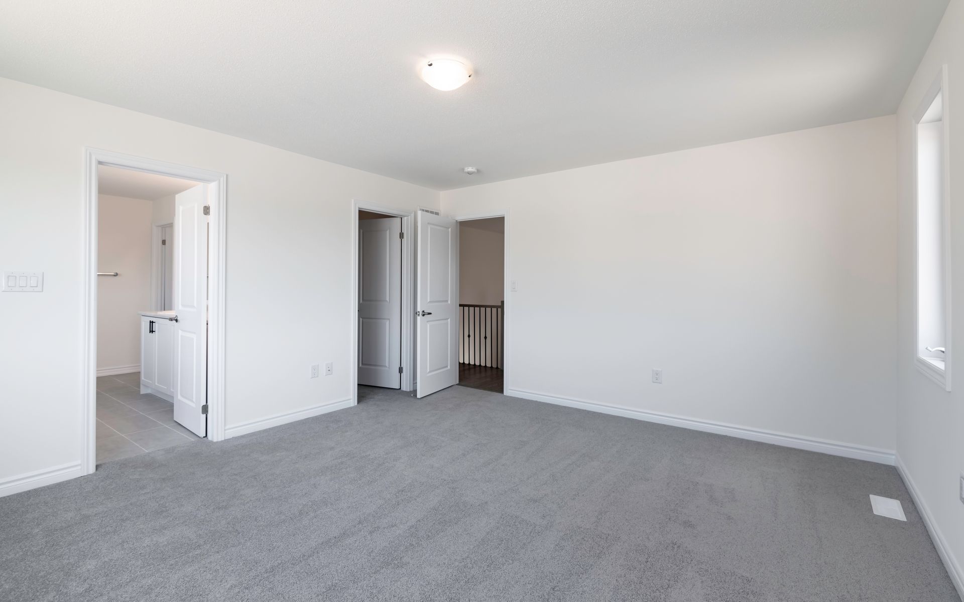 An empty bedroom with a gray carpet and white walls.