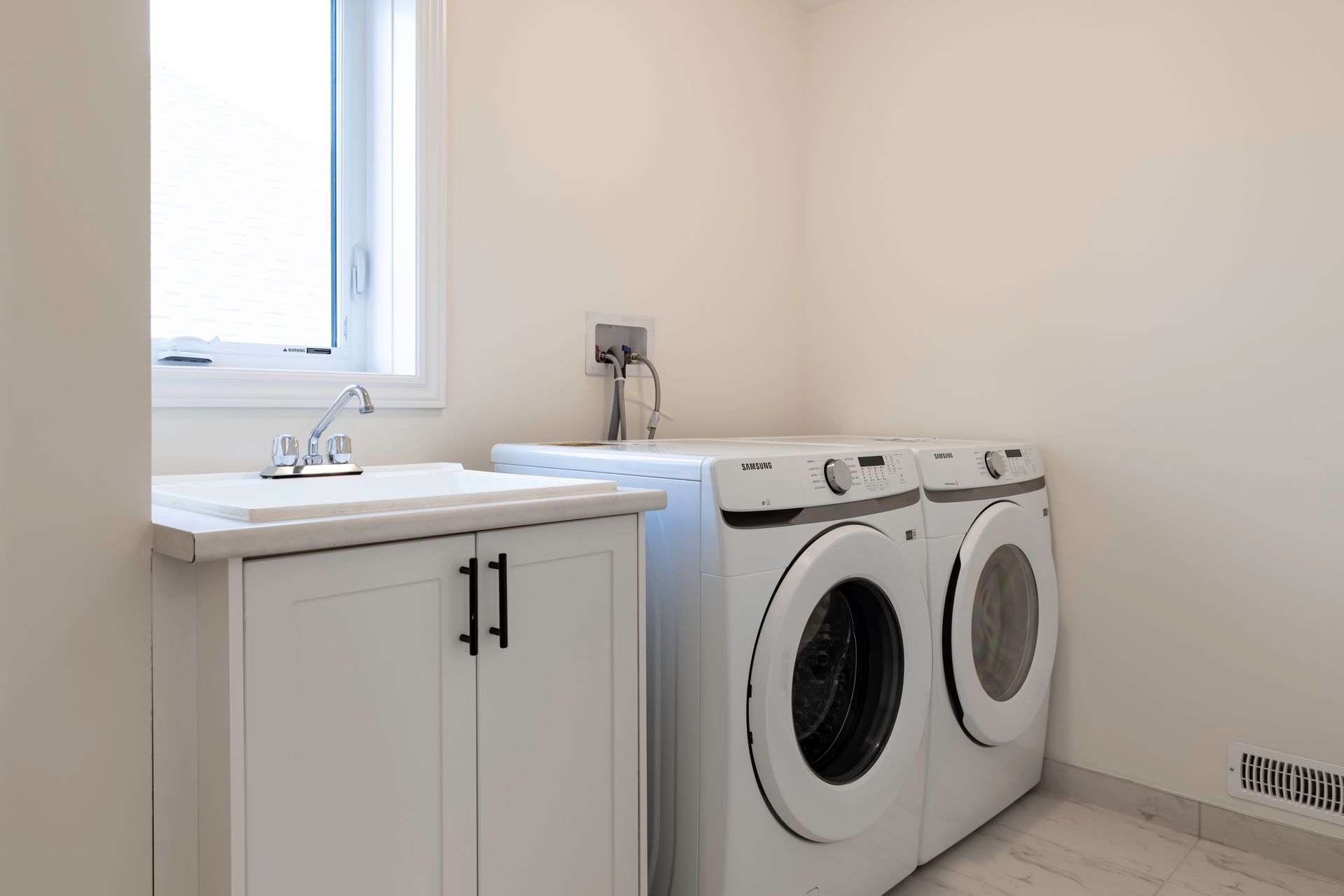 A laundry room with a washer and dryer and a sink.