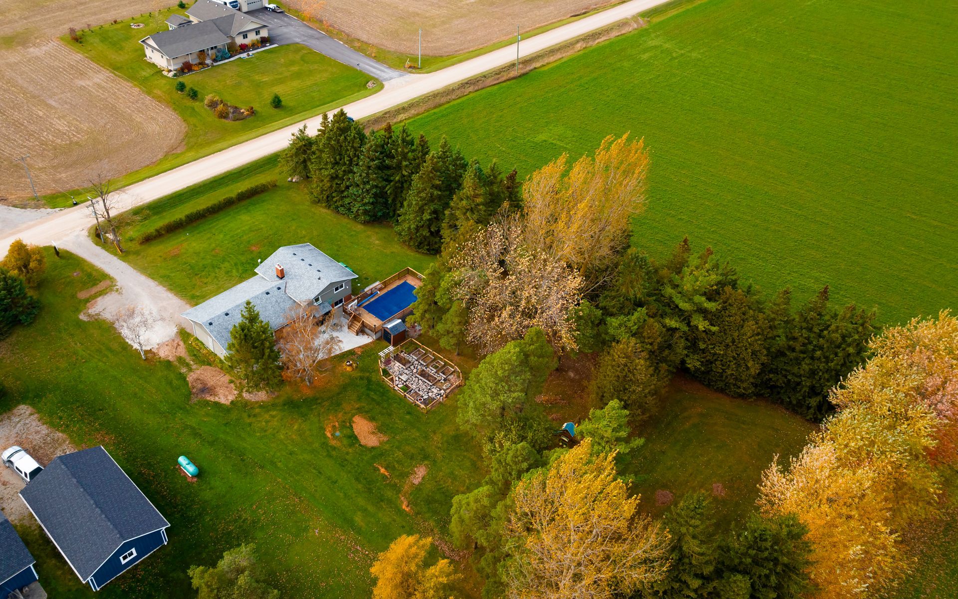 An aerial view of a house in the middle of a field surrounded by trees.