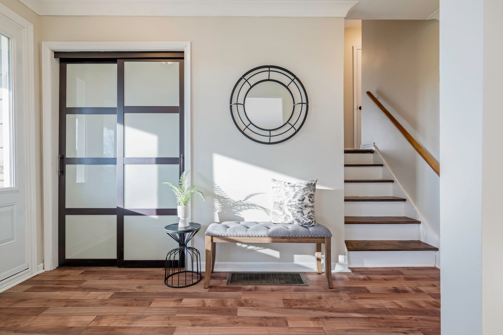 A hallway with a bench and stairs in a house.