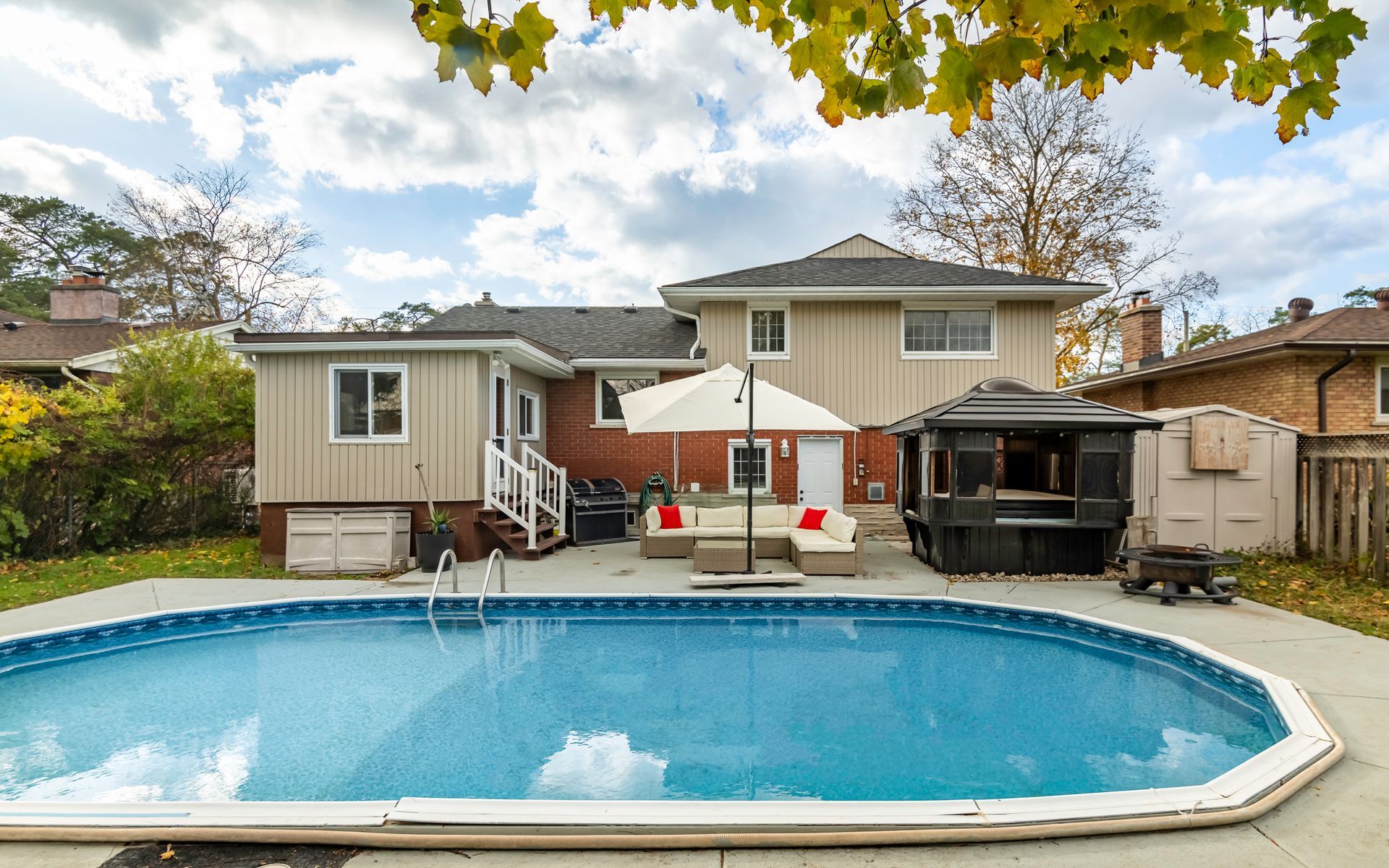 A large swimming pool is in the backyard of a house.