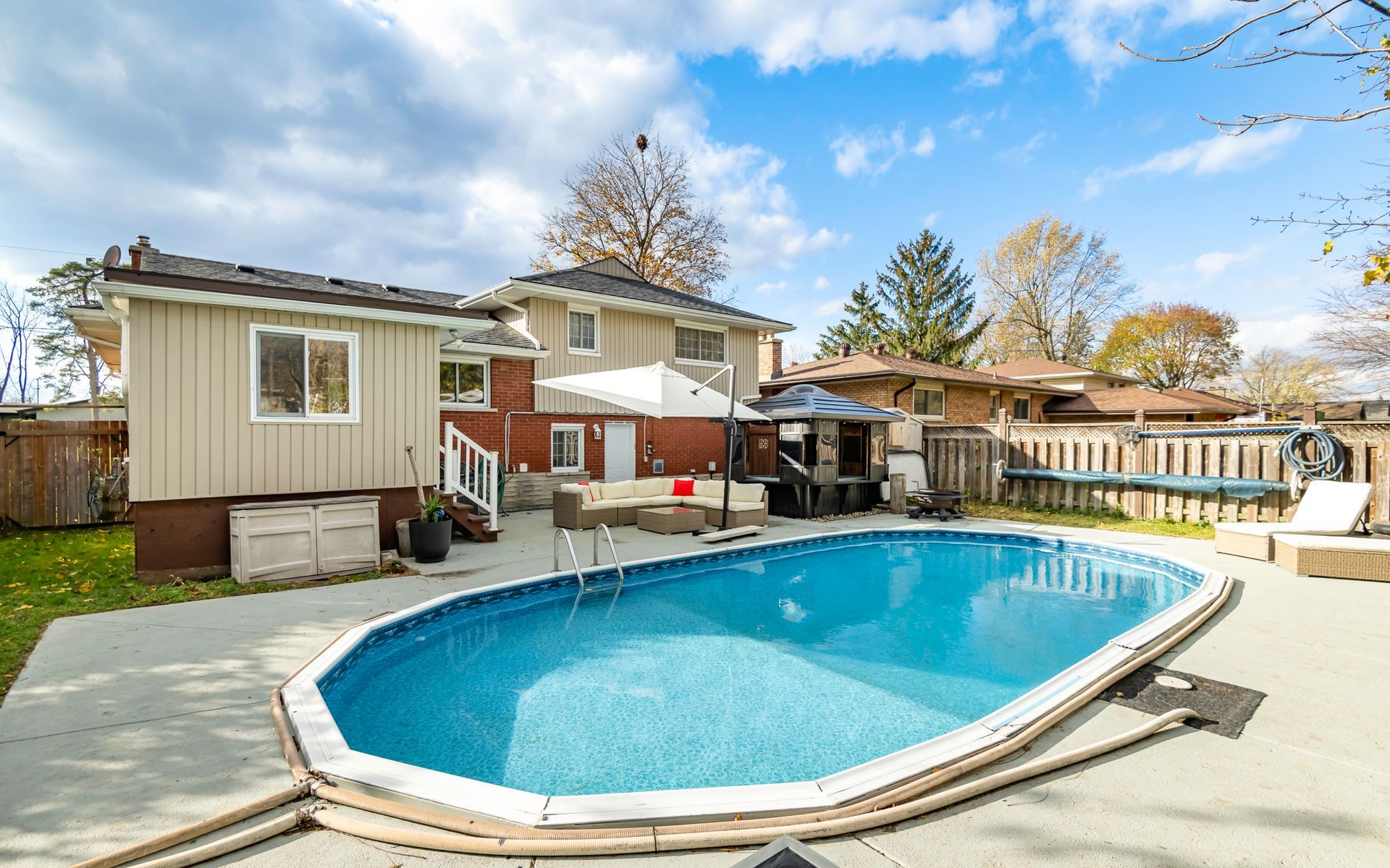 A large swimming pool is in the backyard of a house.