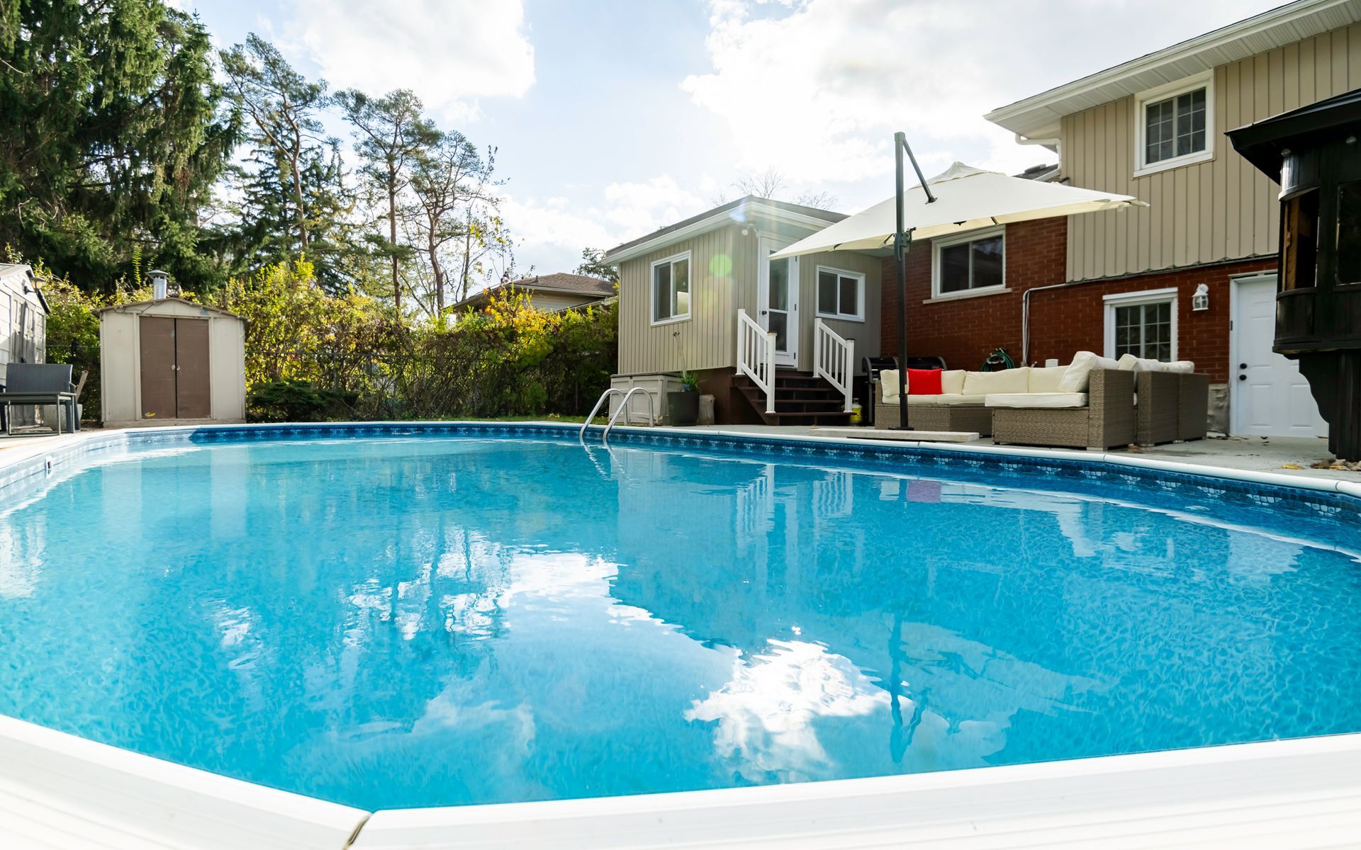 A large swimming pool is in the backyard of a house.