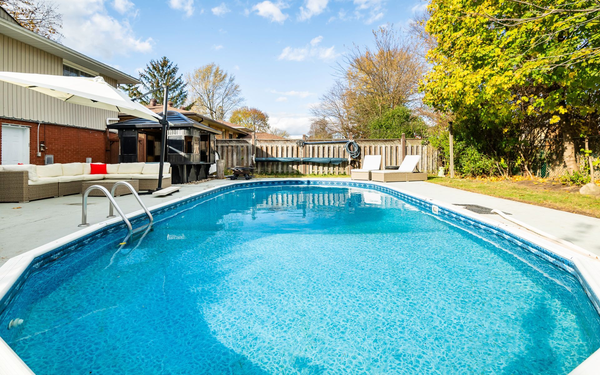 There is a large swimming pool in the backyard of a house.
