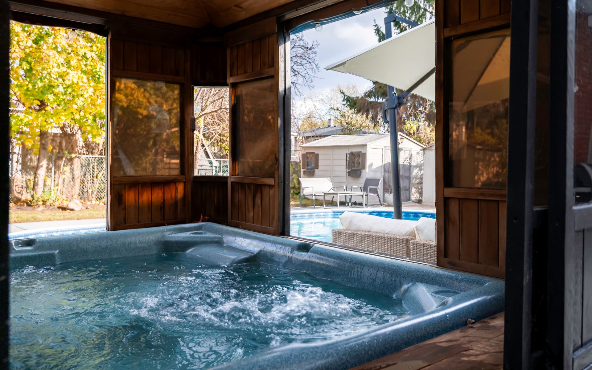 A hot tub is sitting inside of a gazebo next to a pool.