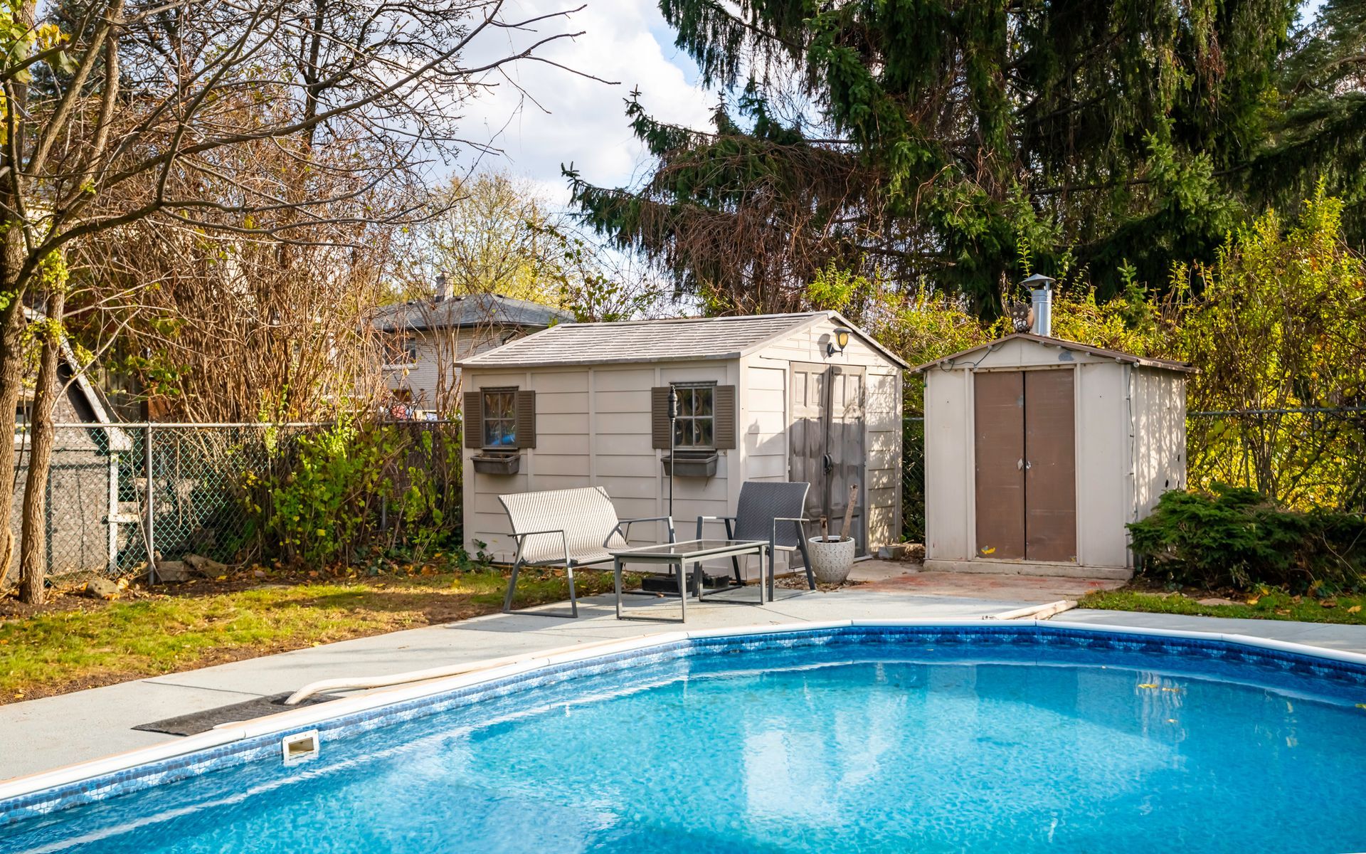 There is a swimming pool in the backyard with a shed in the background.