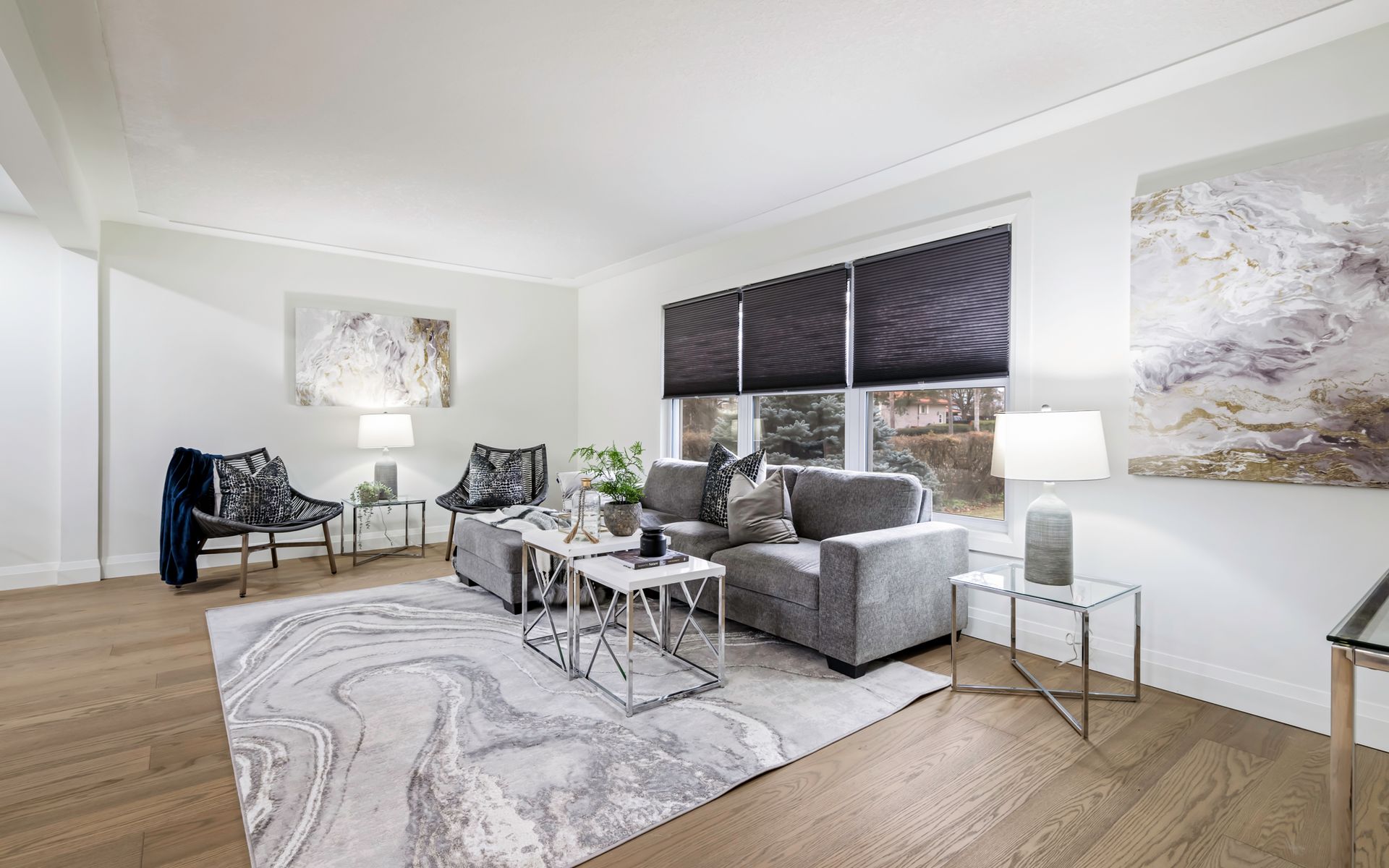 A living room with a couch , chairs , tables and a rug.