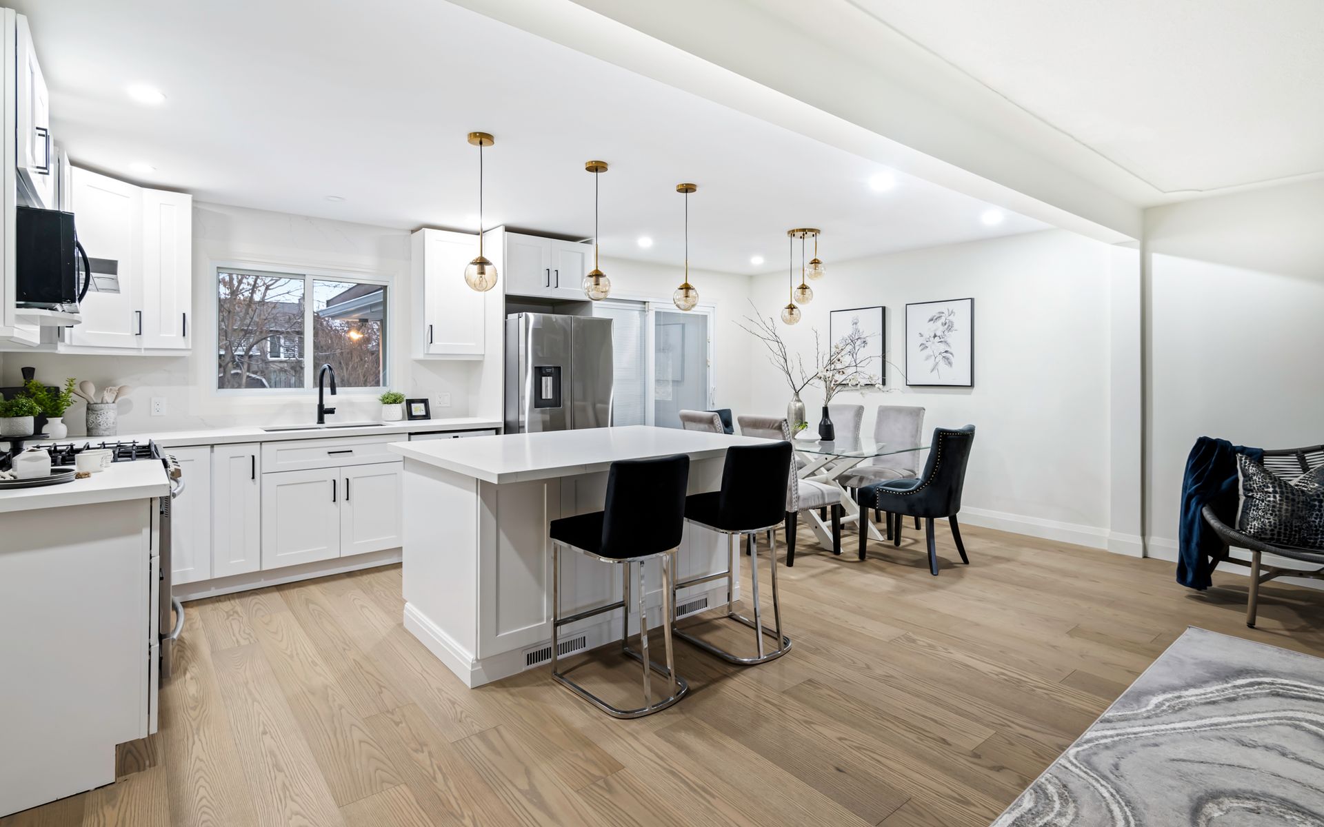 A kitchen and dining room in a house with hardwood floors and white cabinets.