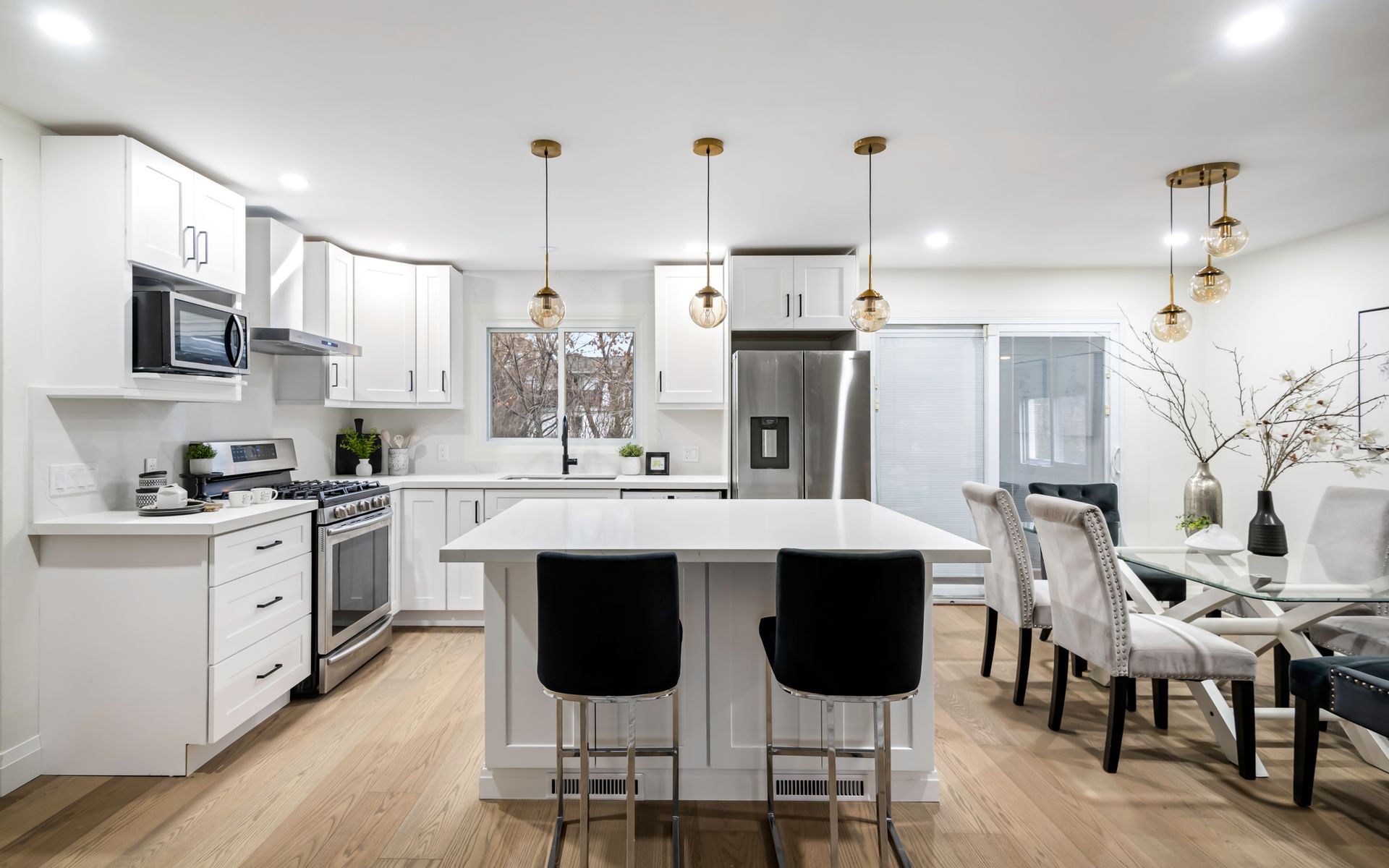 A kitchen with white cabinets , stainless steel appliances , and a large island.