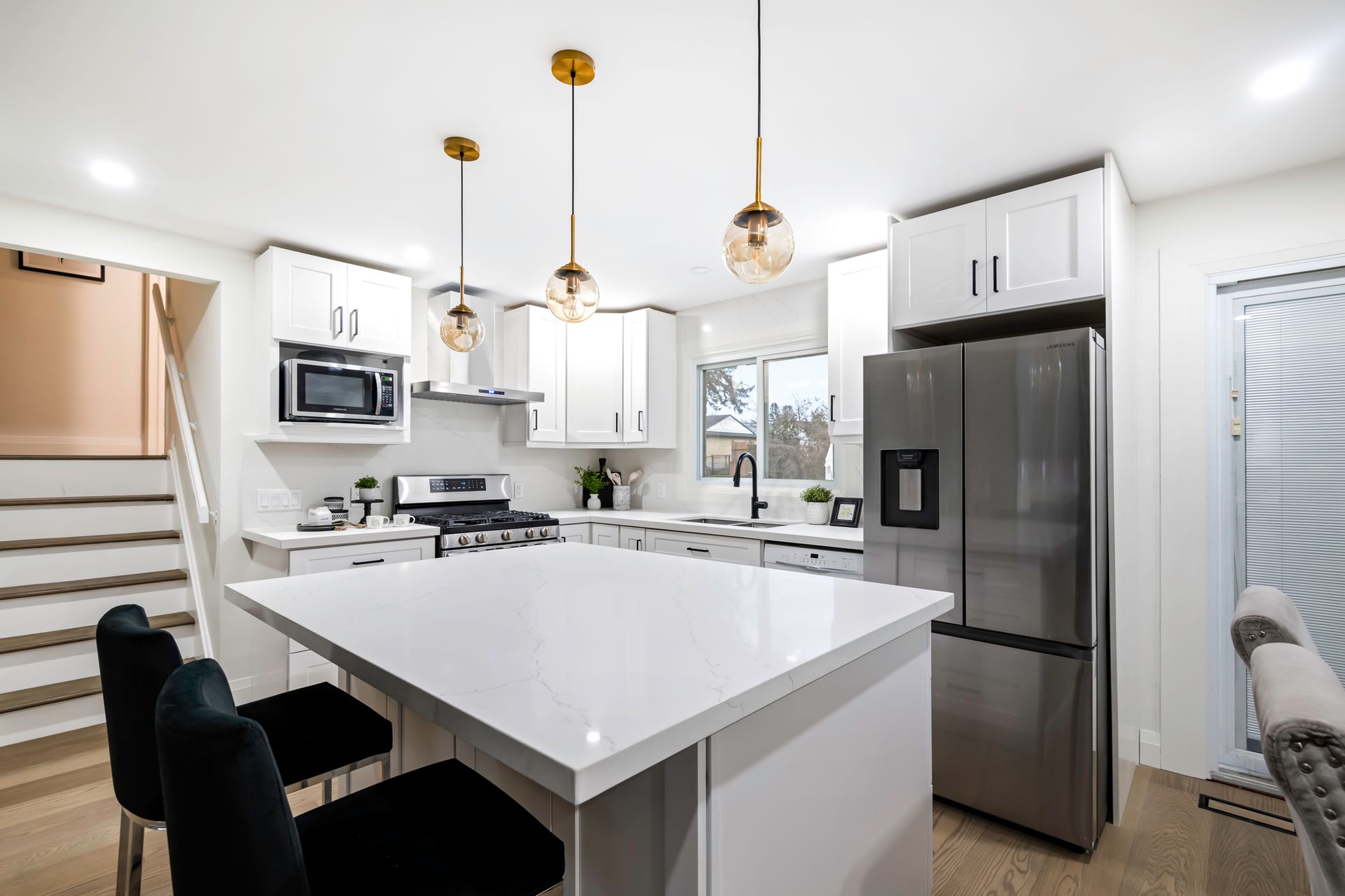 A kitchen with white cabinets , stainless steel appliances and a large island.