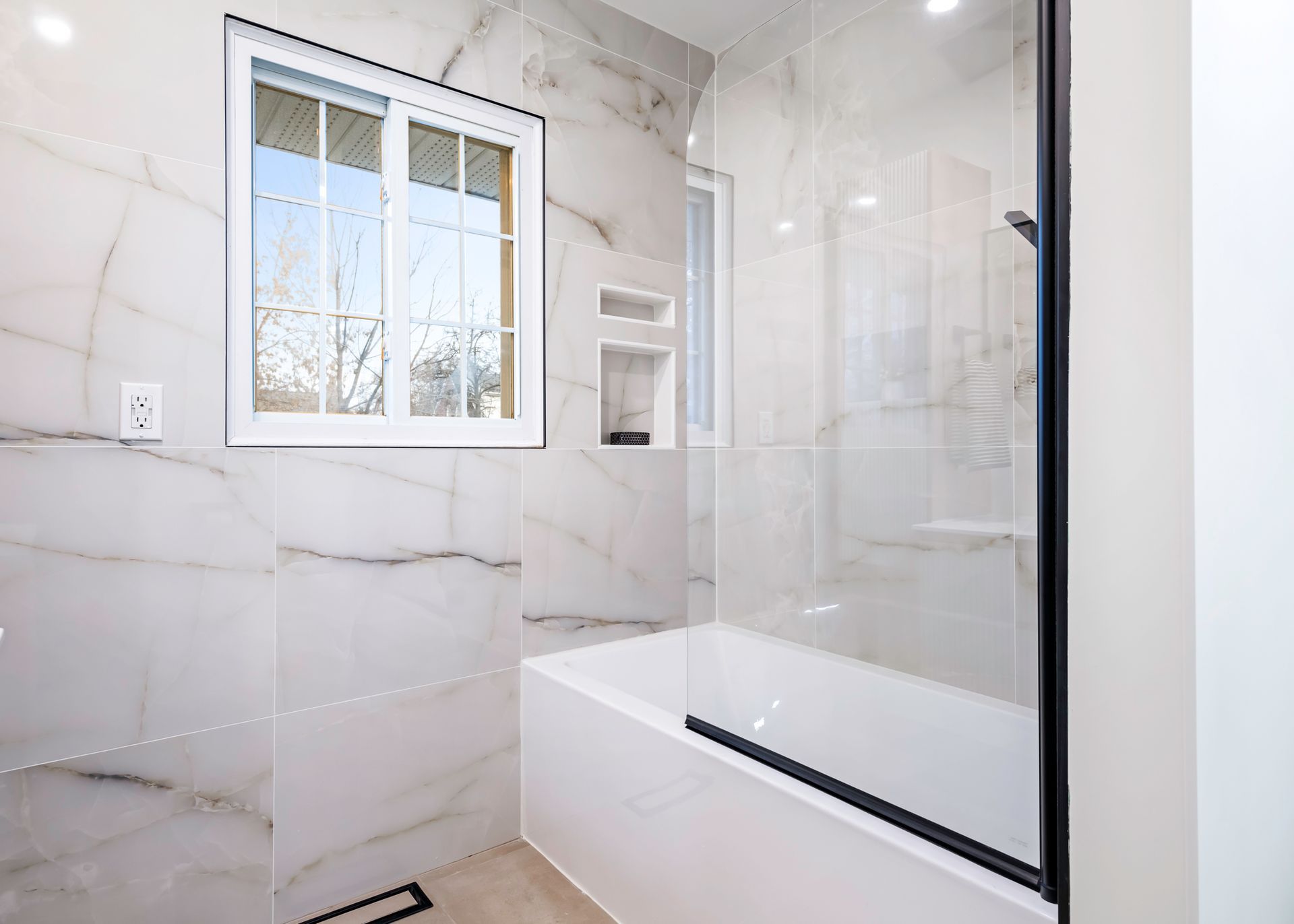 A bathroom with a tub and a shower with a glass door.