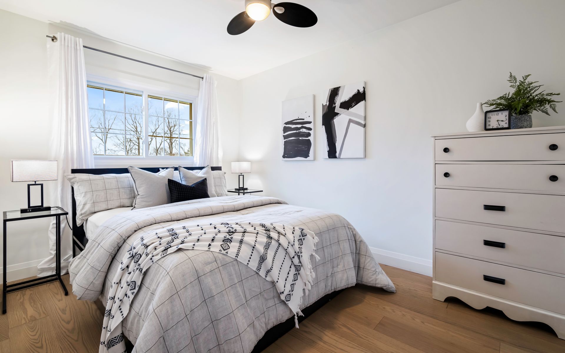 A bedroom with a bed , dresser , nightstand and ceiling fan.