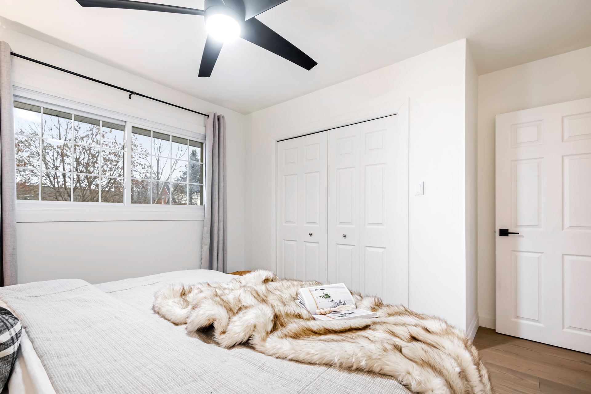A bedroom with a bed and a ceiling fan.