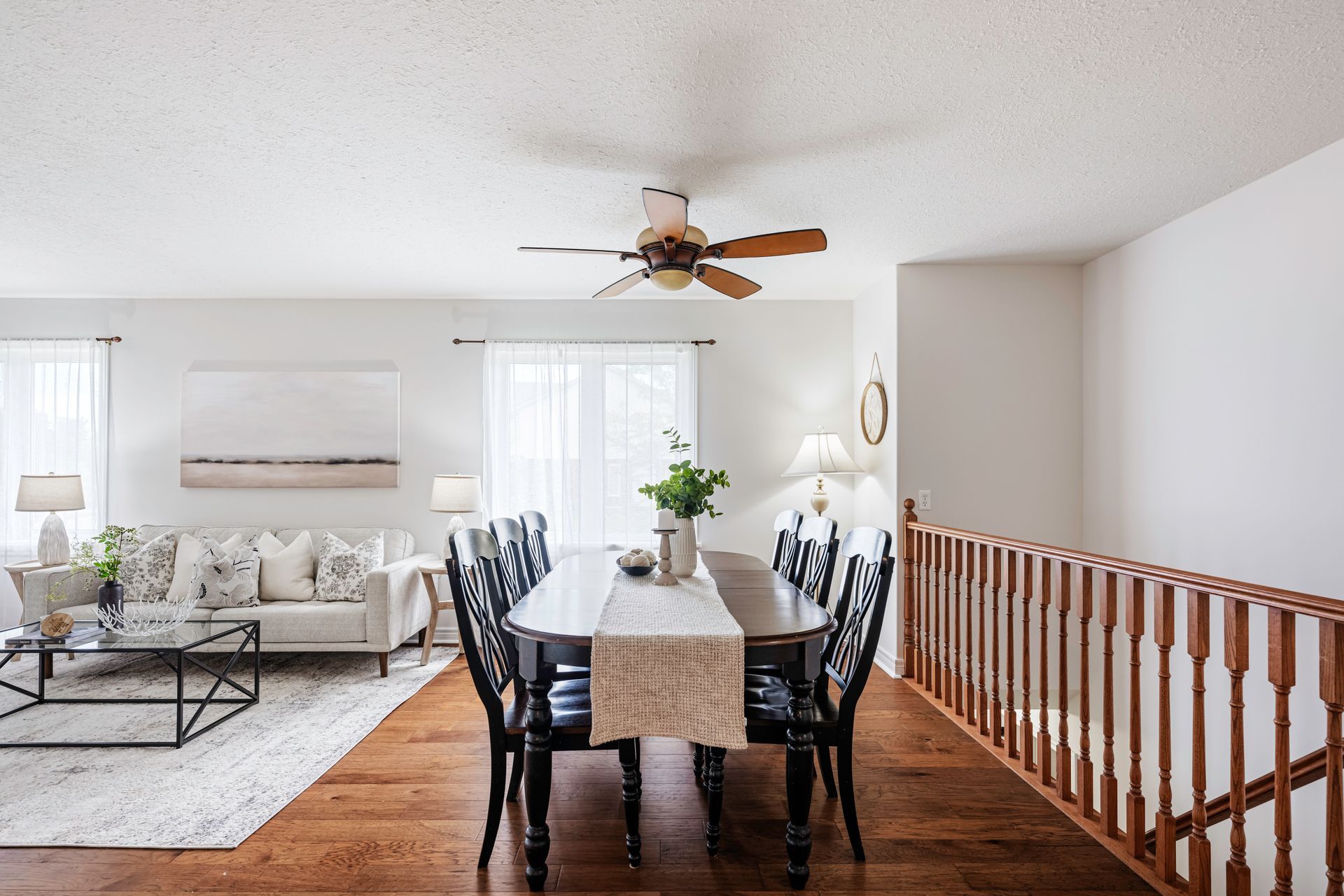A living room with a dining table and chairs and a ceiling fan.