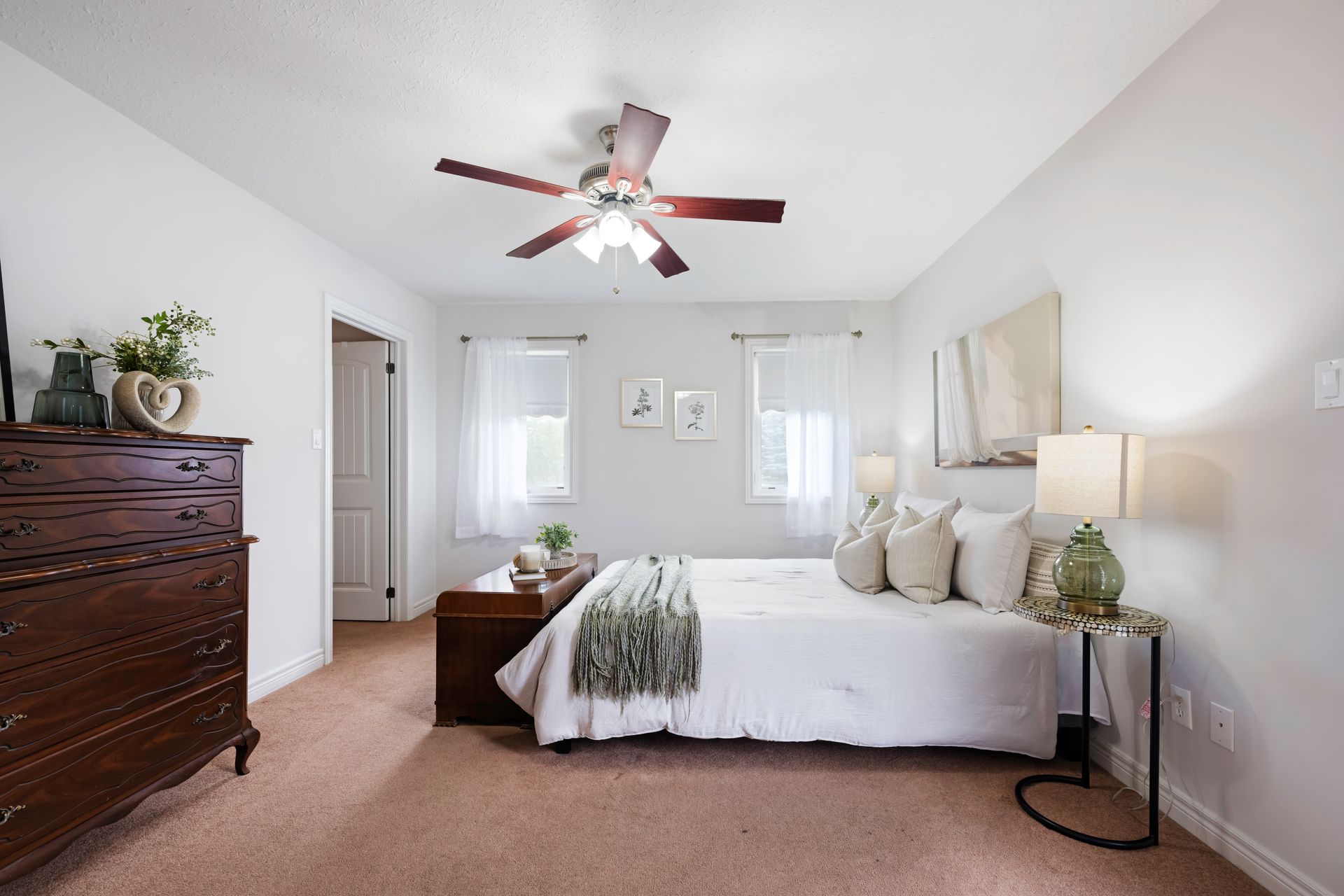 A bedroom with a bed , dresser , and ceiling fan.